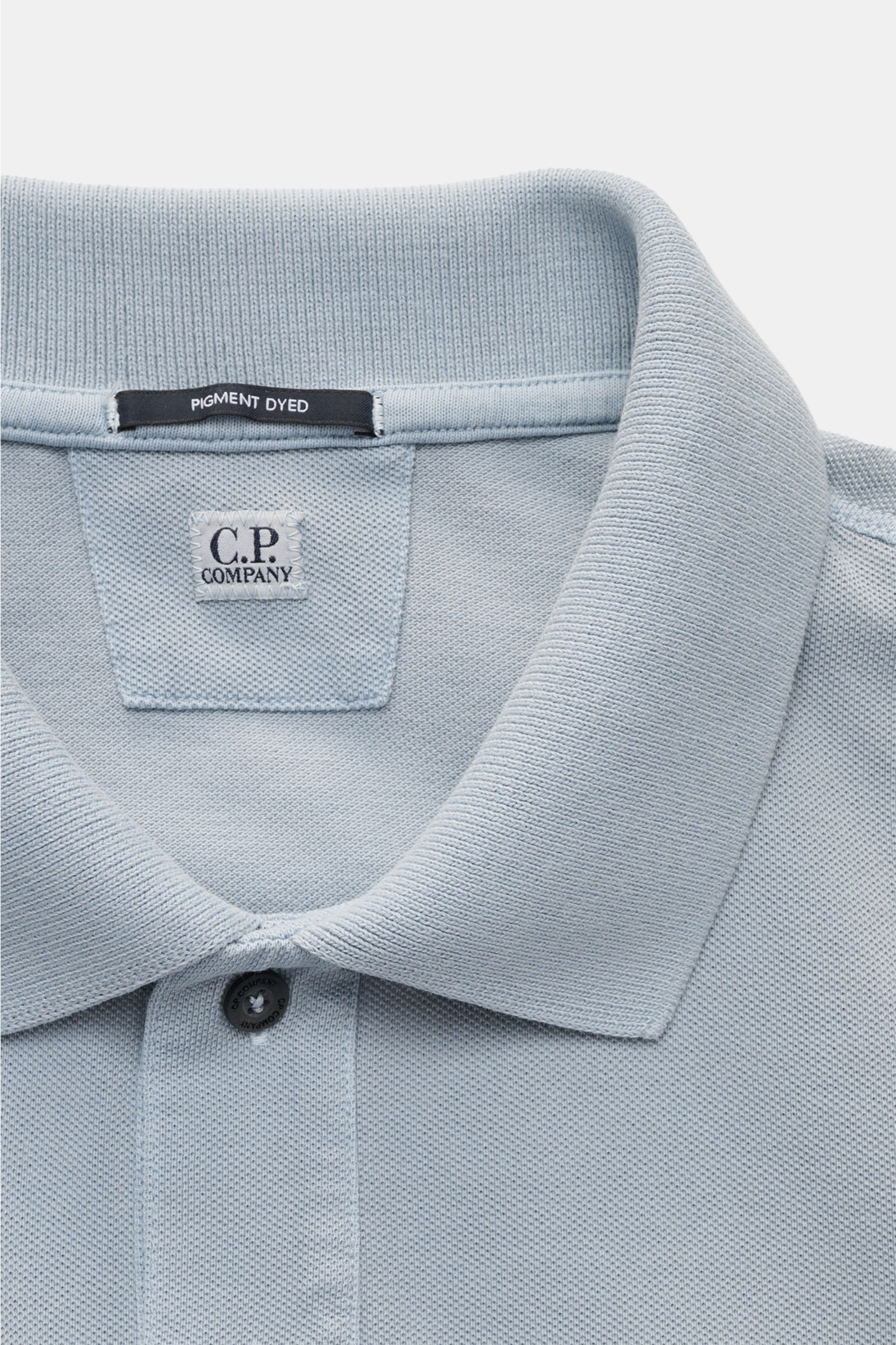 C.P. Company Poloshirt rauchblau, Nahaufnahme von Kragen, zwei Knöpfen, Weblabel und weichem Baumwoll-Piqué mit Pigment-Dye-Färbung.