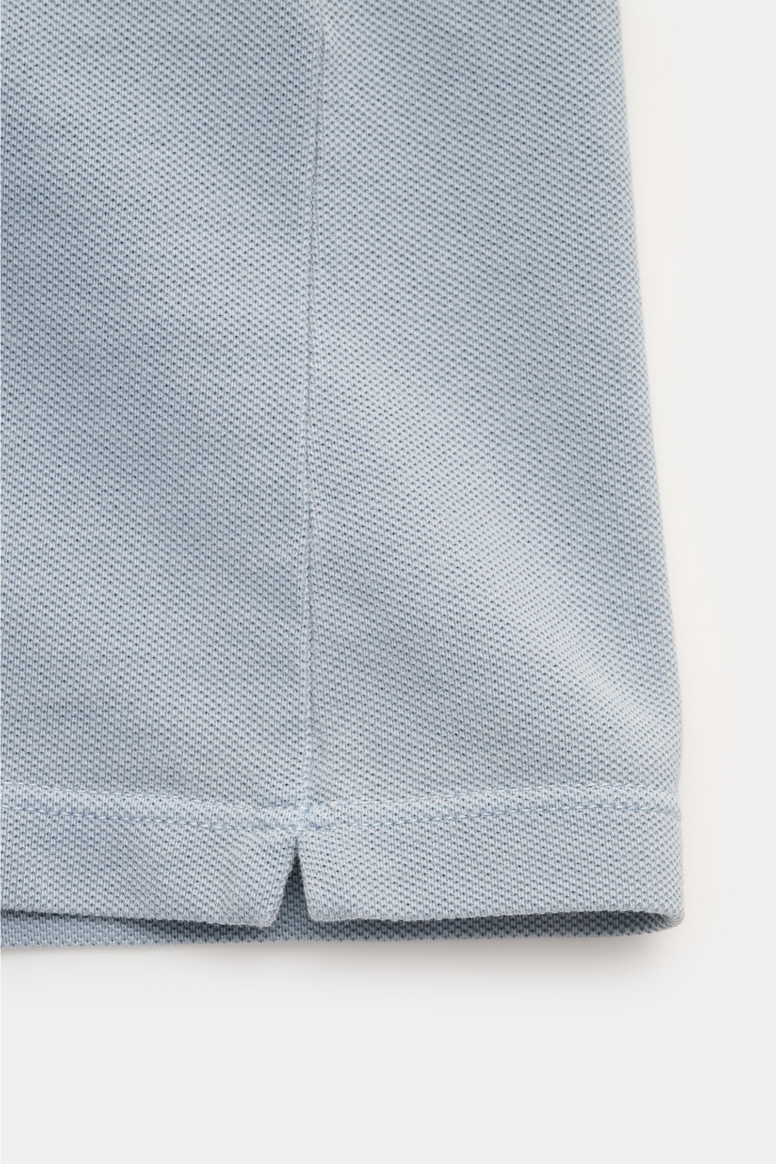 C.P. Company Poloshirt rauchblau, Detailaufnahme des unteren Saums mit kurzen Saumschlitzen, weicher Baumwoll-Piqué, Slim Fit.