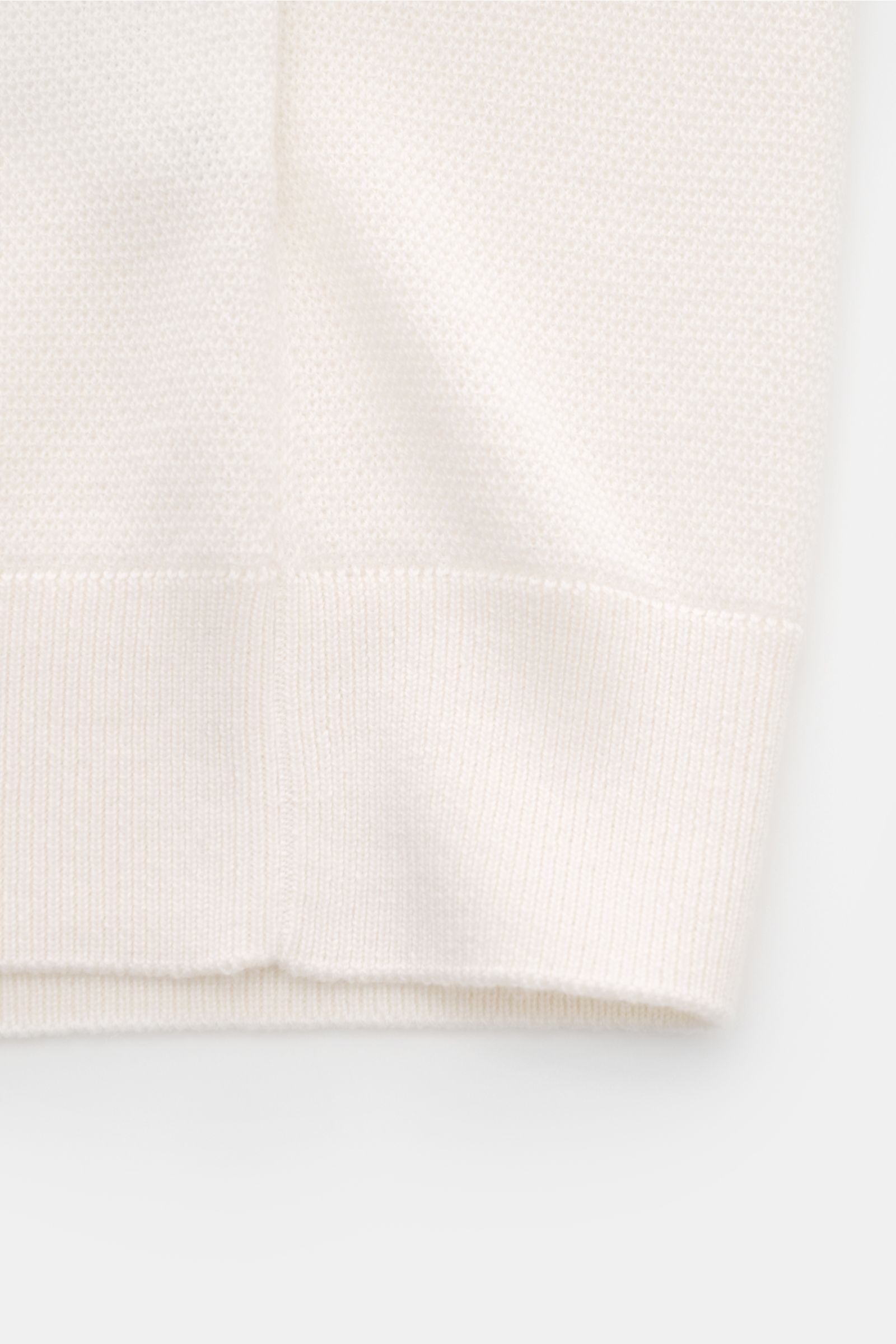 Close-up image from the side of the offwhite Iris von Arnim Kurzarm-Strickpolo 'Pavion' showing the fine knit texture and ribbed hem. Luxuriöser Allrounder: Das edle Strickpolo von IRIS VON ARNIM verbindet Exklusivität mit unvergleichlichem Komfort und wi