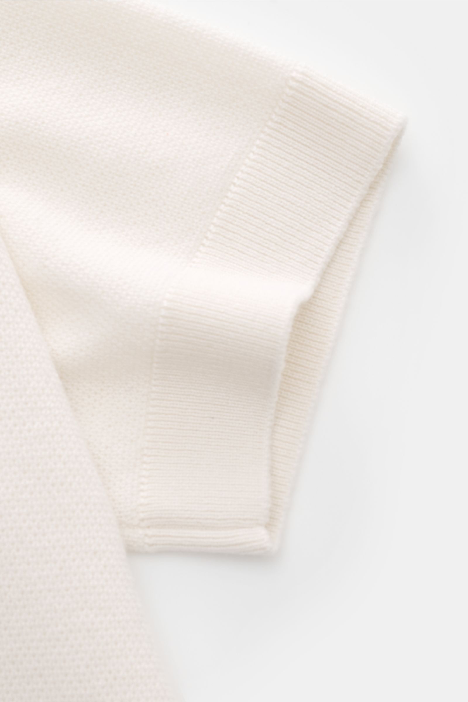 Close-up side view of the short sleeve and textured knit fabric of the Iris von Arnim Kurzarm-Strickpolo 'Pavion' offwhite, showcasing its luxurious cashmere and silk blend, soft feel, regular fit, classic polo collar, and two-button placket. Luxuriöse
