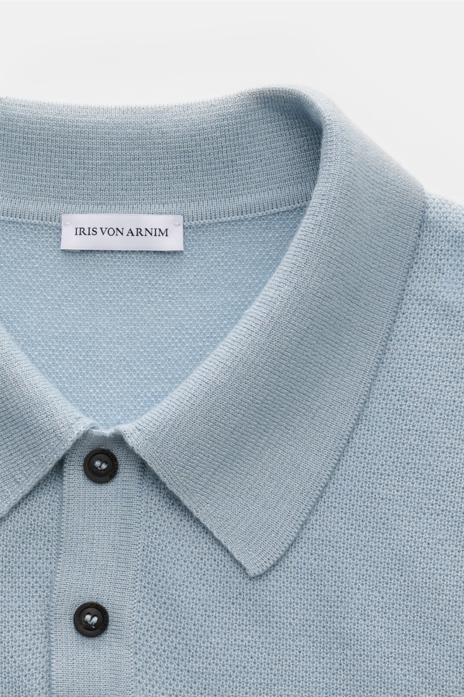 Close-up front view of the light blue Iris von Arnim Kurzarm-Strickpolo 'Pavion' showing its classic polo collar and two-button placket. Luxuriöser Allrounder: Das edle Strickpolo von IRIS VON ARNIM verbindet Exklusivität mit unvergleichlichem Komfort und