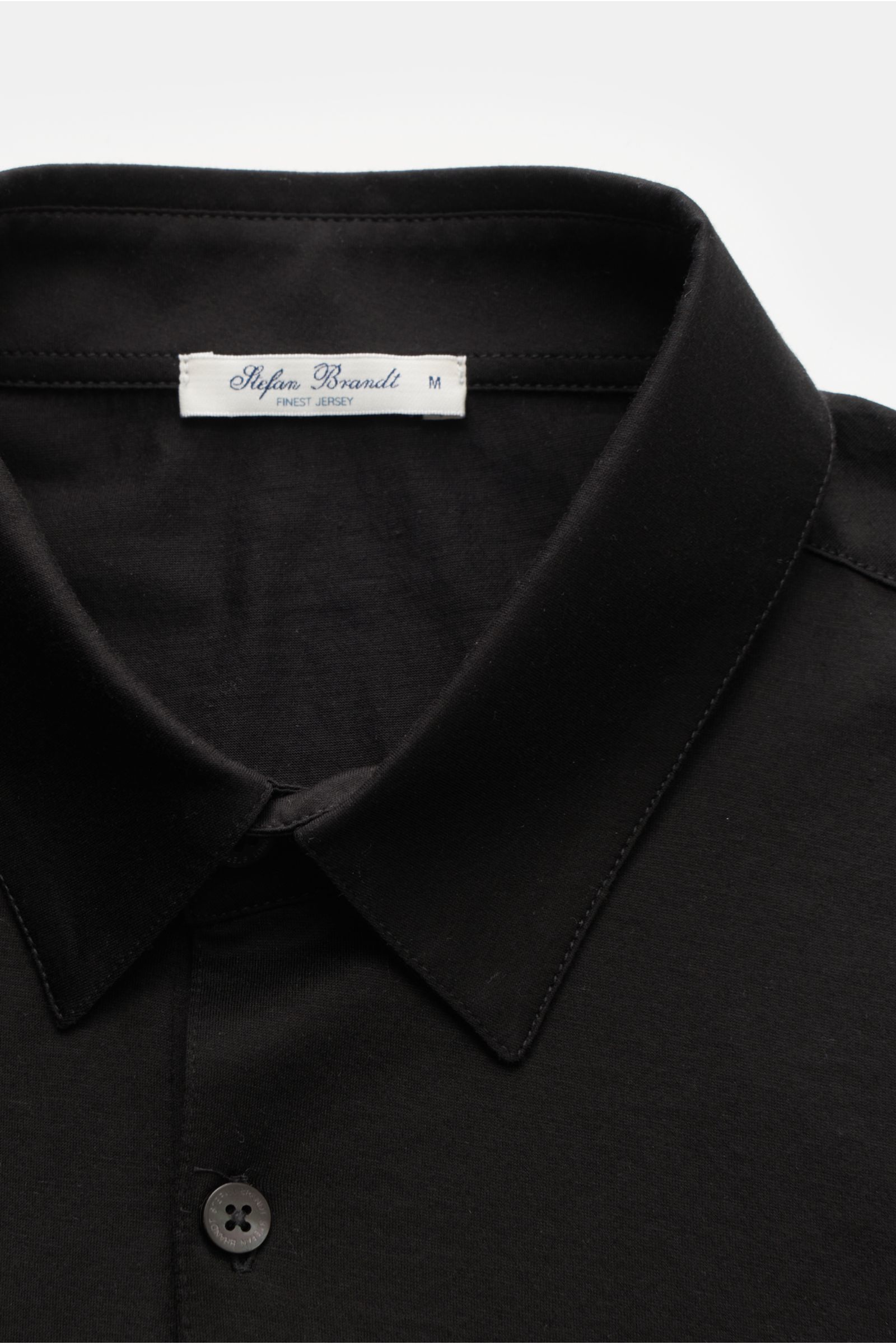 Close-up front view of the Stefan Brandt Jersey-Poloshirt 'Luca' schwarz, showcasing the black slim-fit polo collar, three-button placket, and soft organic Pima cotton fabric with stretch for comfort. Das exklusive Jersey-Poloshirt von STEFAN BRANDT be
