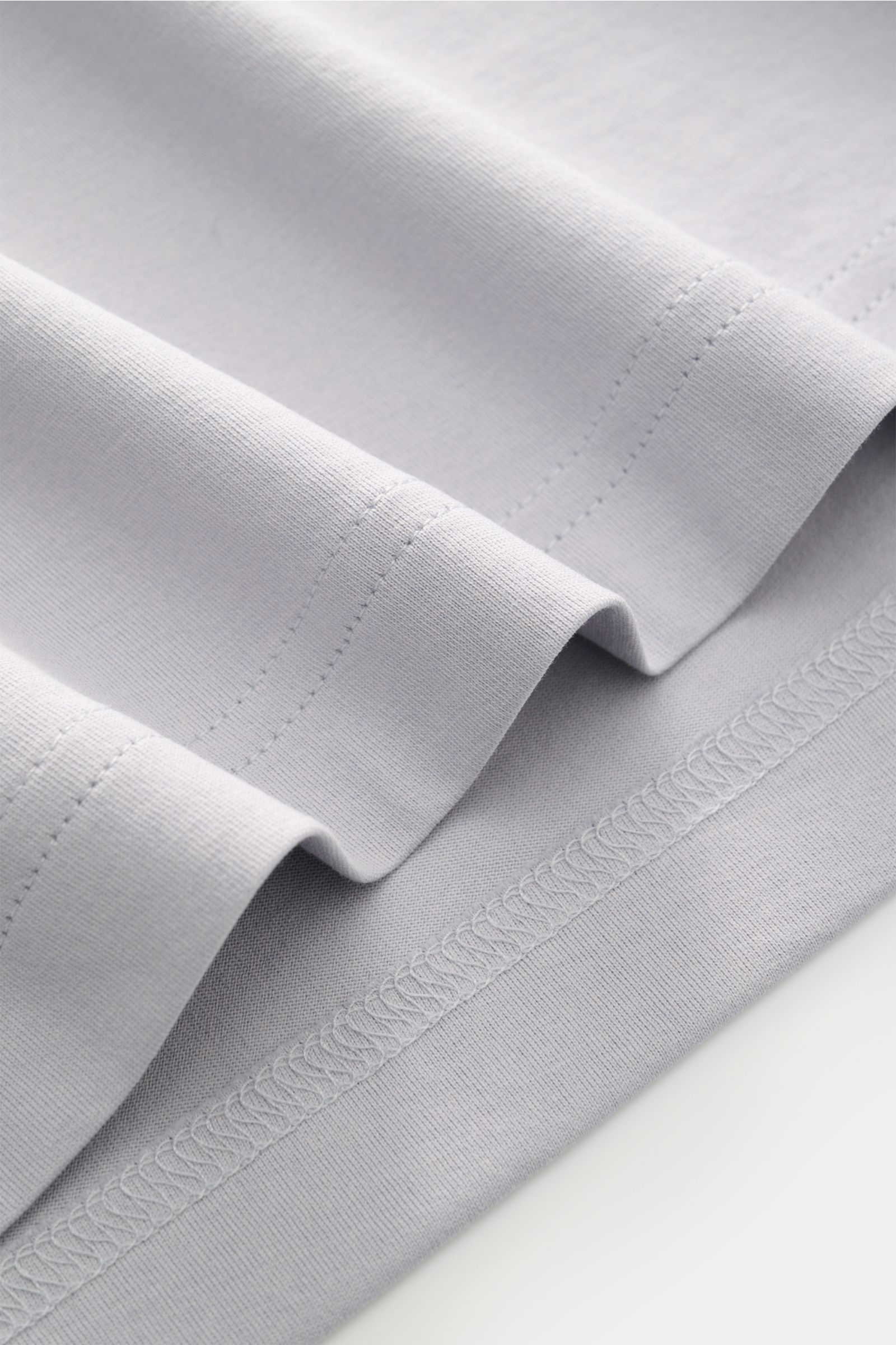 Nahaufnahme des hellgrauen Stefan Brandt Jersey-Poloshirts 'Luca' von unten, zeigt feine Jersey-Qualität aus reiner Pima-Baumwolle mit geschmeidigem Griff und Saumdetails.