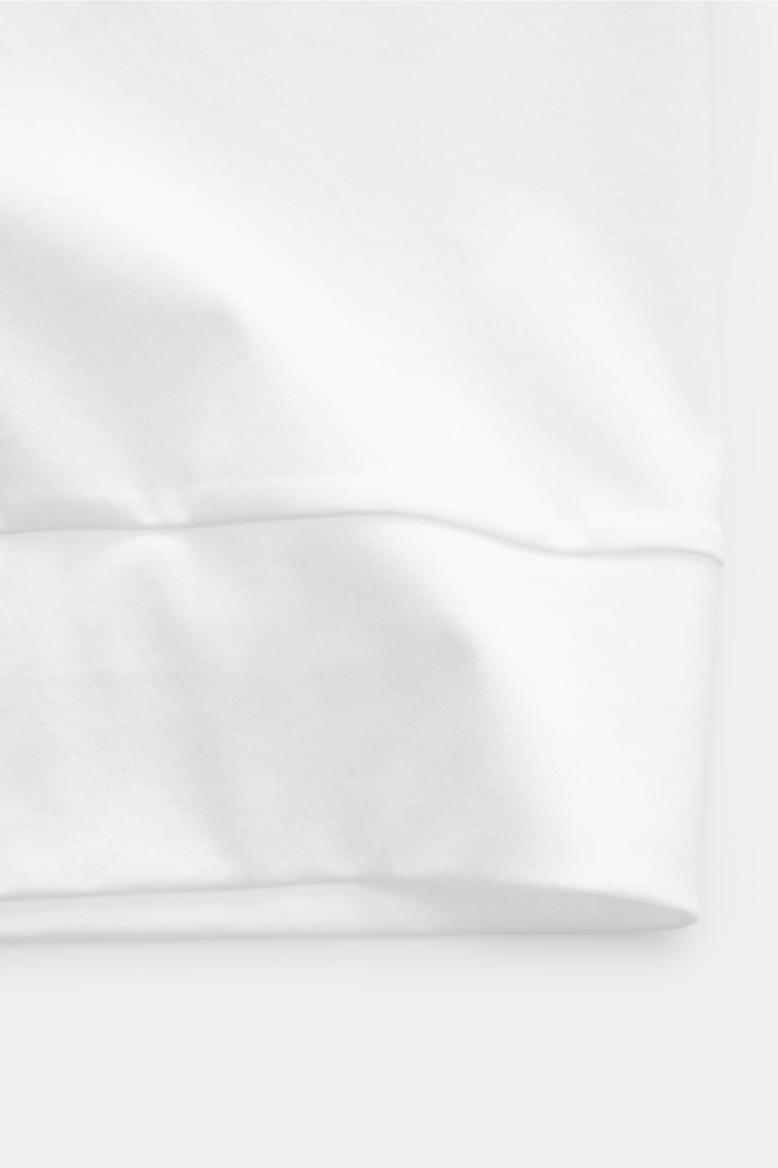 Close-up bottom hem view of Stefan Brandt Jersey-Poloshirt 'Luca' weiß, featuring fine Pima cotton jersey, slim fit, and flexible cuffs.

Description: Feinster Komfort für jeden Tag: Das exklusive Jersey-Poloshirt 'Luca' von 