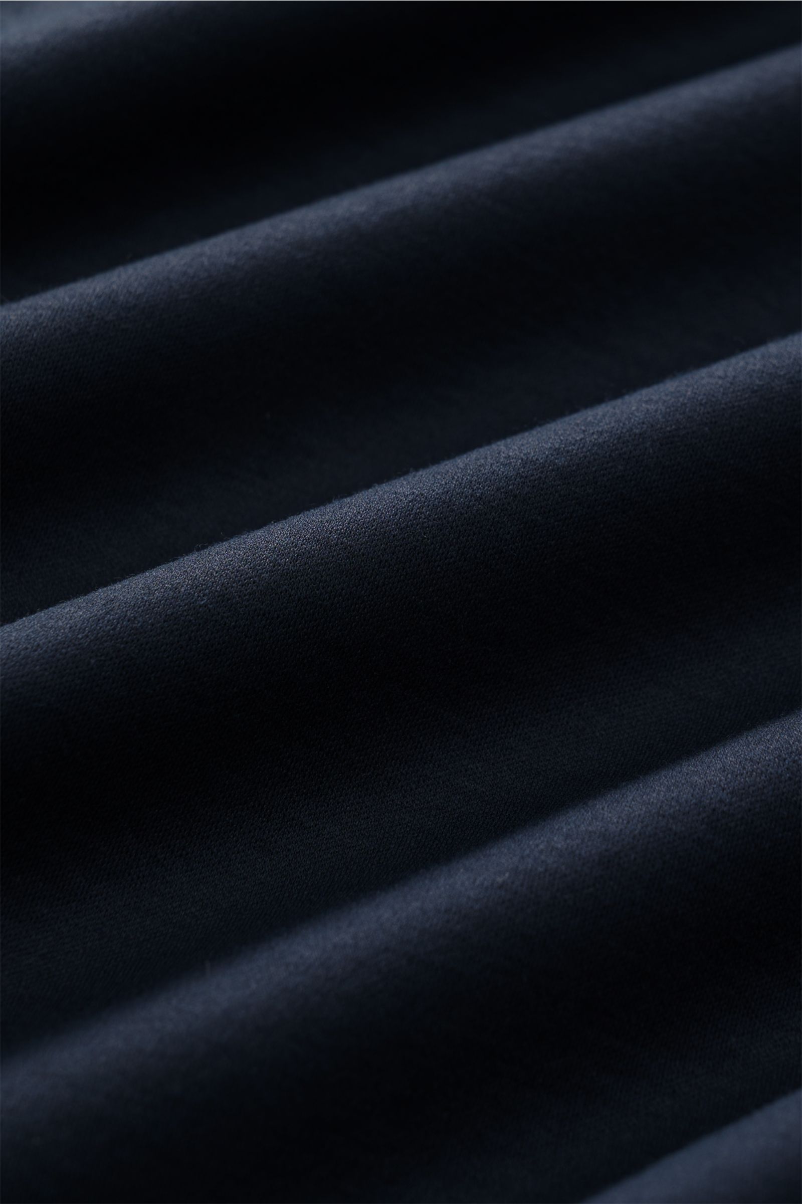 Close-up, angled view of dark navy fabric folds showing texture and softness of the Stefan Brandt Jersey-Poloshirt 'Luca' dark navy. Feinster Komfort für jeden Tag: Das exklusive Jersey-Poloshirt 'Luca' von 