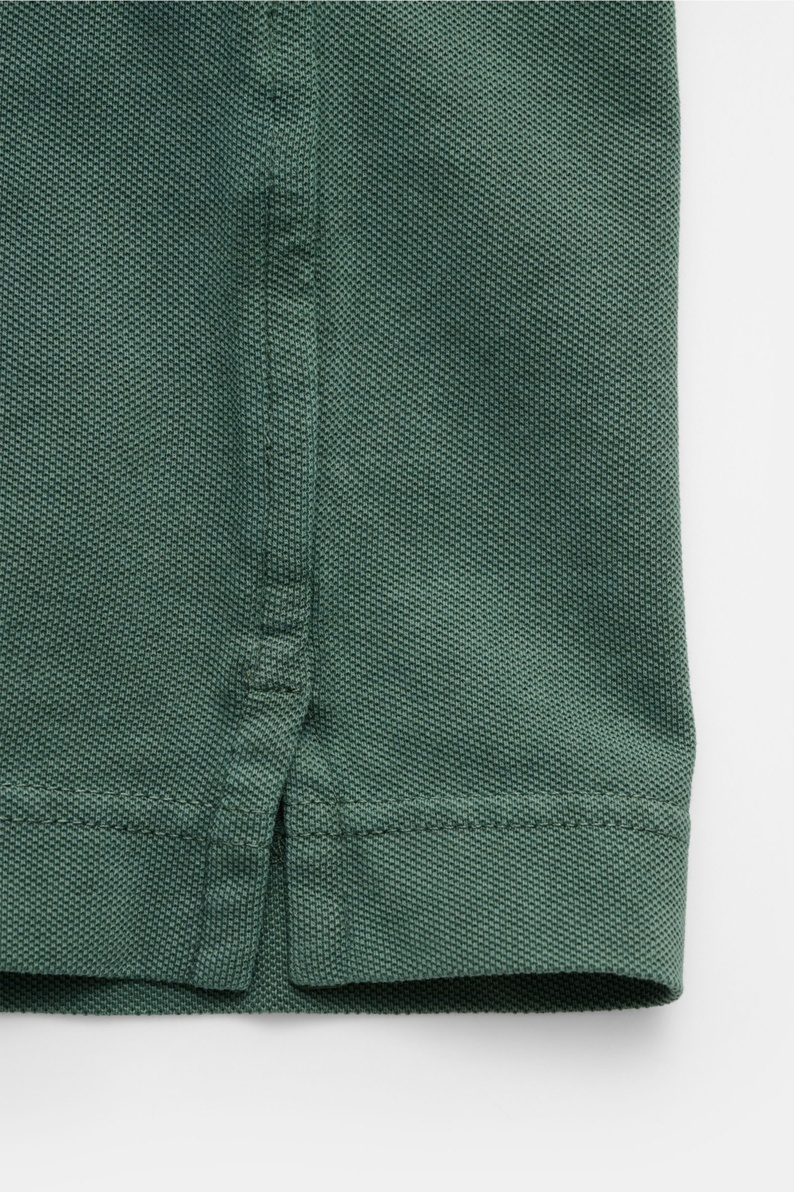 Nahaufnahme des dunkelgrünen Della Ciana Poloshirts aus Baumwoll-Piqué, Frontdetails von Saum und Knopfleiste, sommerliches Basic.