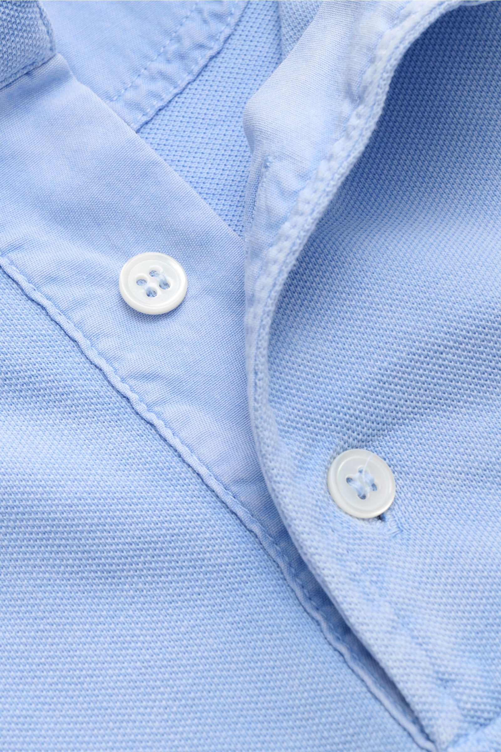 Della Ciana Poloshirt hellblau in Nahaufnahme von oben, stückgefärbt, reine Baumwolle, feine Piqué-Struktur, Drei-Knopf-Leiste, weicher Griff.