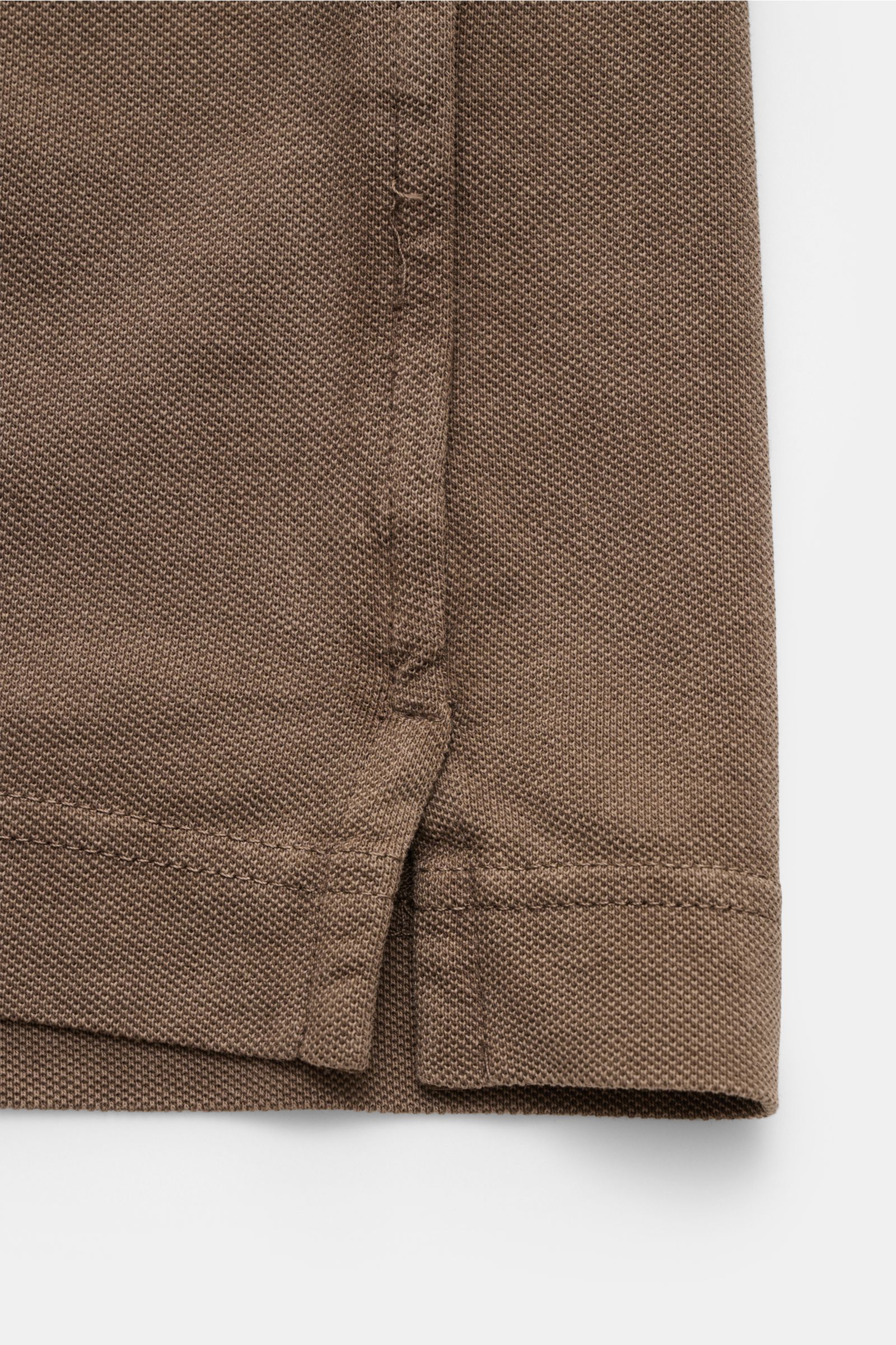 Nahaufnahme des seitlichen Saums mit Saumschlitzen des braunen Della Ciana Poloshirt, garment dyed Baumwoll-Piqué Sommer-Basic.