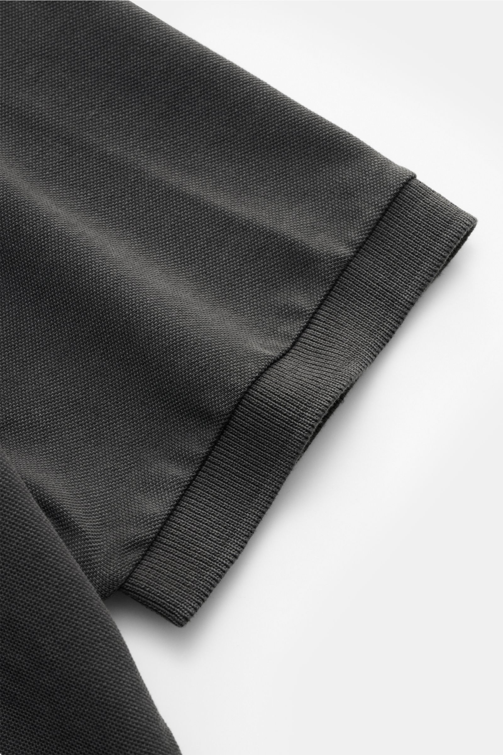 Della Ciana Poloshirt dunkelgrau, Detailaufnahme des elastischen Ärmelbündchens und feiner Baumwoll-Piqué-Struktur, seitliche Saumschlitze sichtbar.