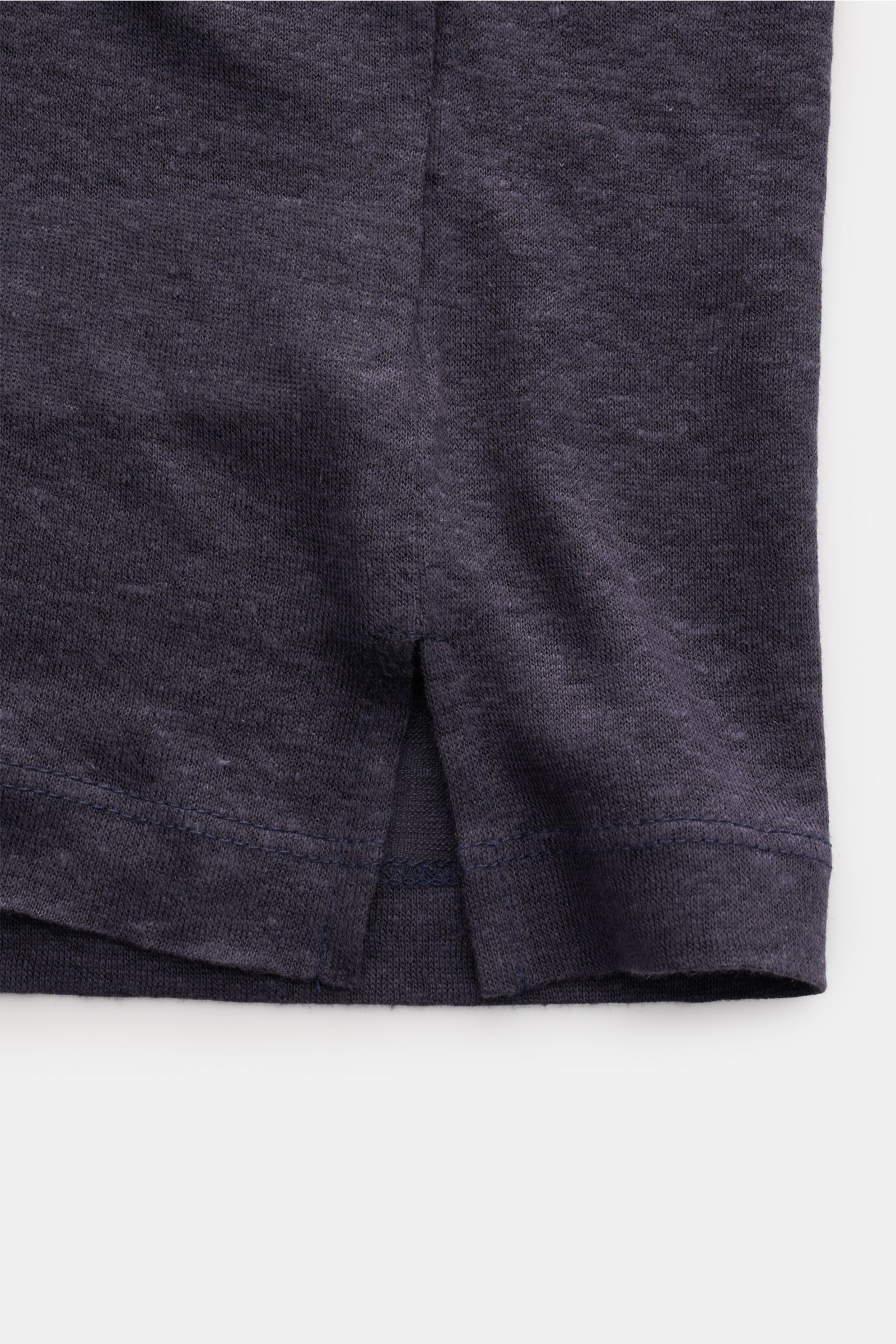 Close-up view of the hem and side slit of the Officine Générale Kurzarm-Strickpolo 'Simon' navy meliert, highlighting the fine knit texture and stitching. Stilvoll durch die Frühlings- und Sommersaison: Das Kurzarm-Strickpolo von OFFICINE GÉNÉRALE ist 