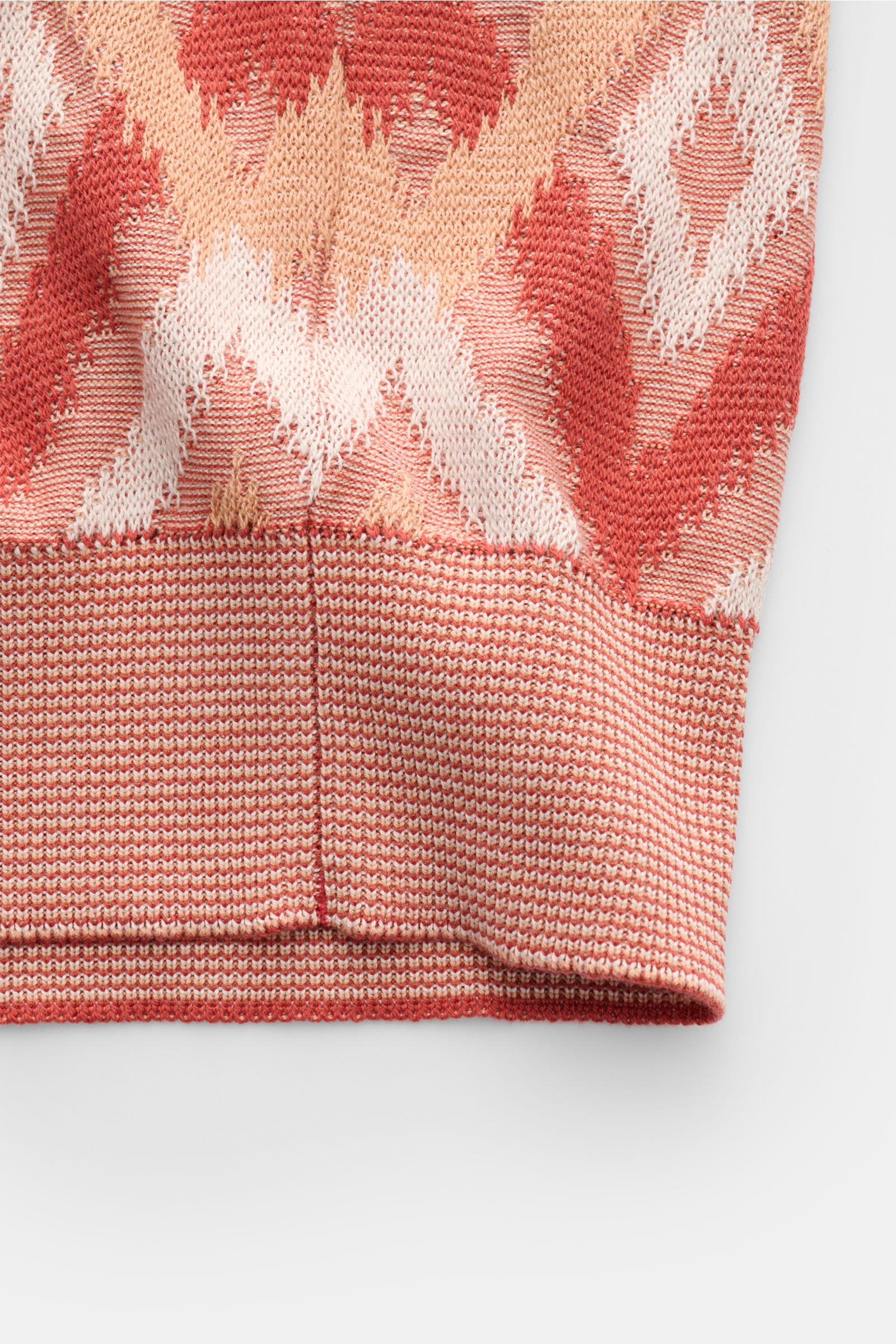 Close-up front view of the hem and pattern of Piacenza 1733 Kurzarm-Strickpolo rot/apricot/offwhite gemustert, showcasing its airy knit with a contrast diamond pattern in silk and cotton.

Ein Hauch von Luxus: Dieses Kurzarm-Strickpolo von PIACENZA 173