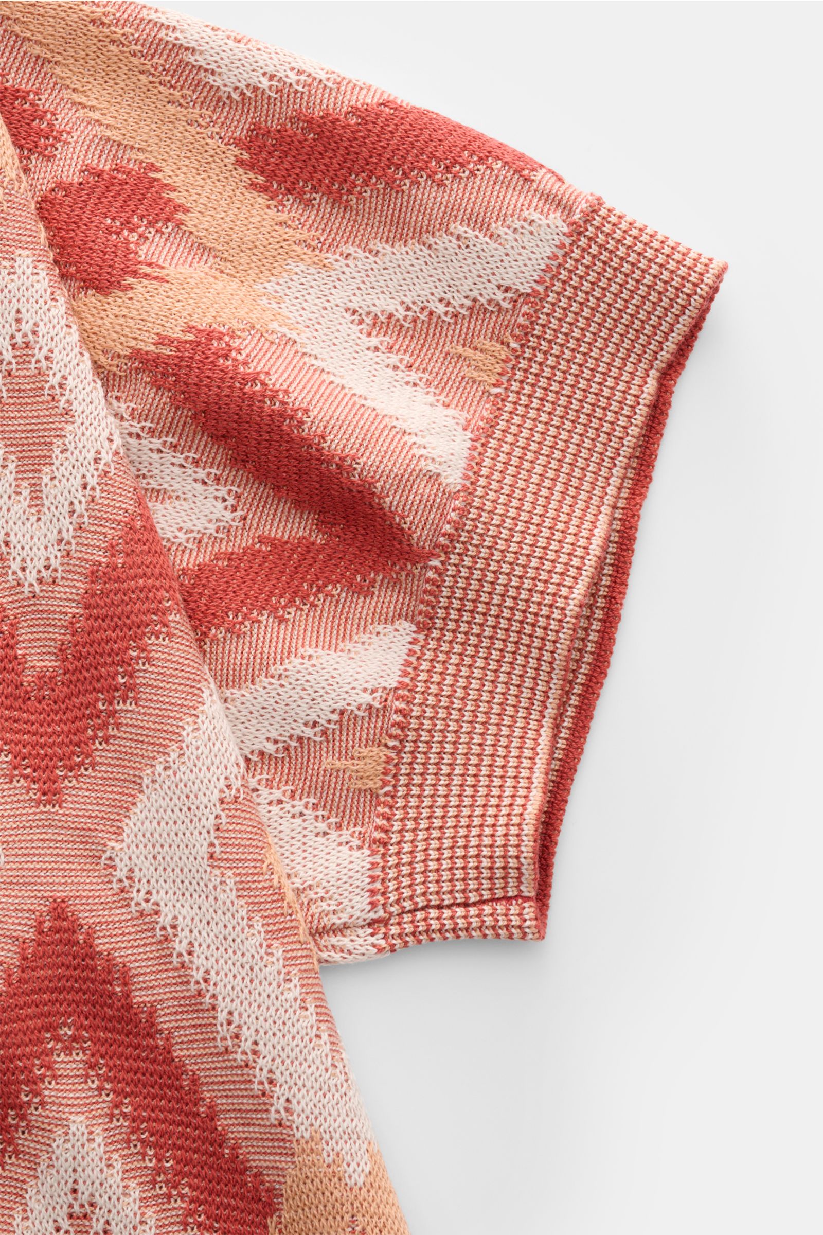 Close-up side view of Piacenza 1733 Kurzarm-Strickpolo rot/apricot/offwhite gemustert showing short sleeve with ribbed cuff and contrast diamond knit pattern in silk-cotton blend.

Ein Hauch von Luxus: Dieses Kurzarm-Strickpolo von PIACENZA 1733 verbin