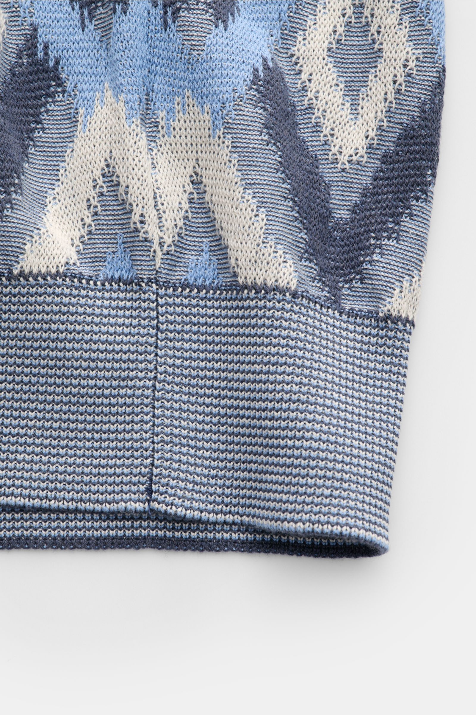 Close-up view of the hem and part of the patterned fabric of the Piacenza 1733 Kurzarm-Strickpolo rauchblau/blau/creme gemustert, showcasing its lightweight knit in silk and cotton with a contrast diamond pattern, slim fit, knitted polo collar, three-butt