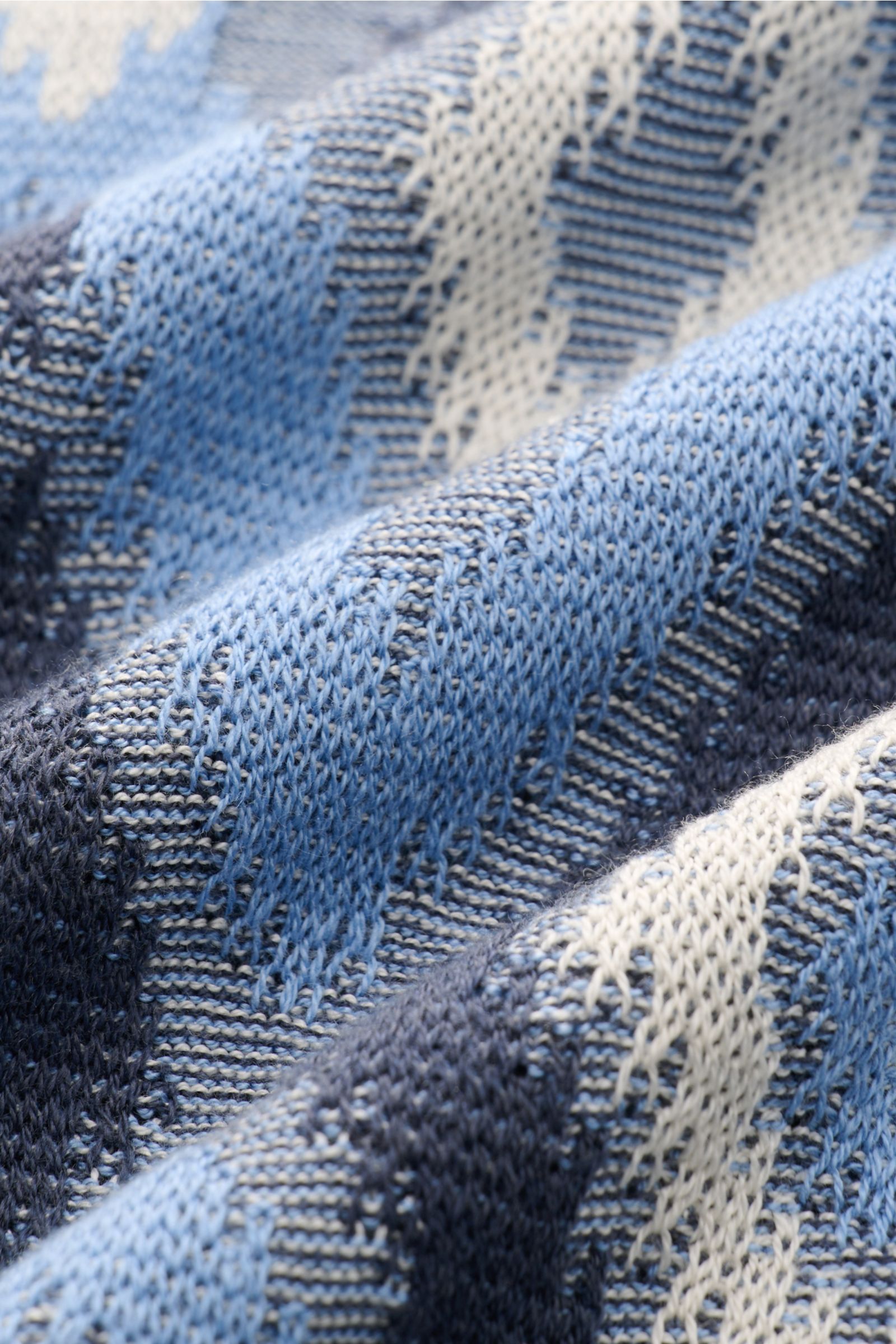 Close-up perspective of the fabric texture of the Piacenza 1733 Kurzarm-Strickpolo rauchblau/blau/creme gemustert, showing a lightweight, airy knit pattern with a contrast diamond motif. Ein Hauch von Luxus: Dieses Kurzarm-Strickpolo von PIACENZA 1733 