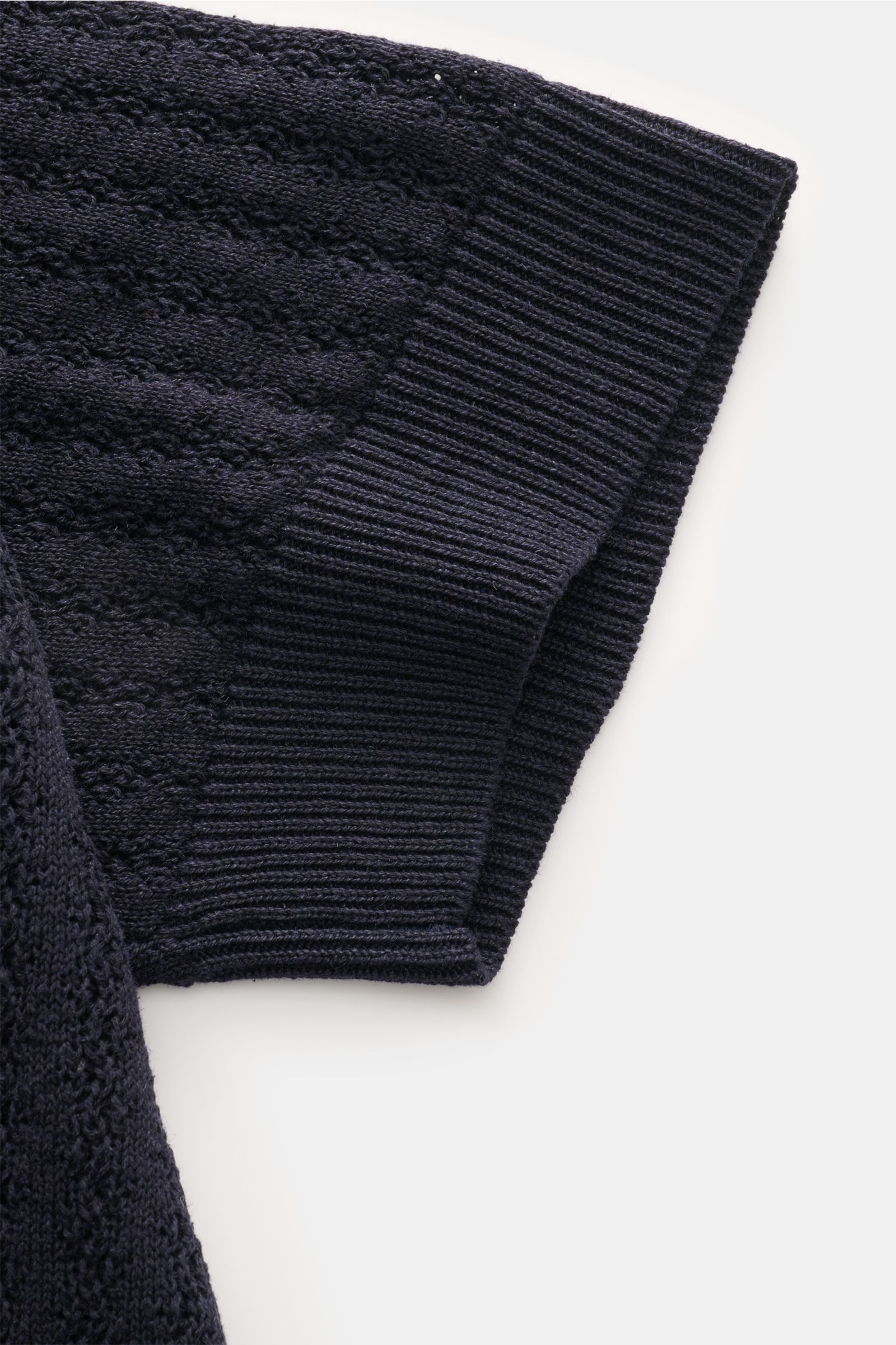 Close-up top view of the sleeve of the Piacenza 1733 Kurzarm-Strickpolo dark navy, showcasing its soft silk-linen blend, medium-fine knit, striped texture, regular fit, classic polo collar, and flexible rib cuffs. Eyecatcher in der Sommersaison: Das Kurza