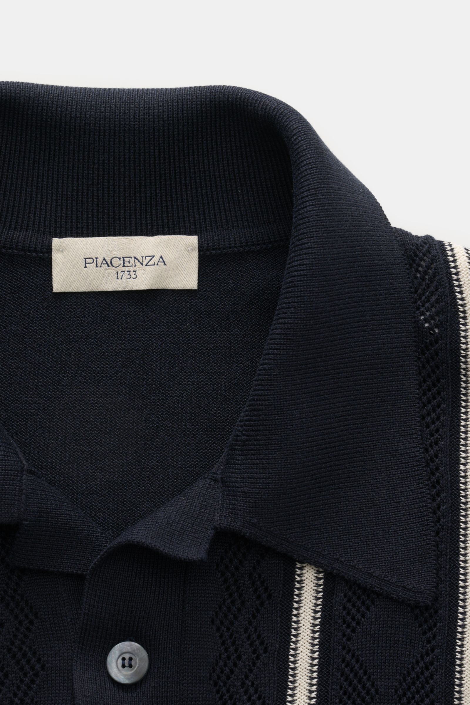 Nahaufnahme des Piacenza 1733 Kurzarm-Strickpolo navy in Regular Fit, Seiden-Baumwoll-Mix, mit Lochstrick, Polokragen, Zwei-Knopf-Leiste und Kontraststreifen, fotografiert von oben.