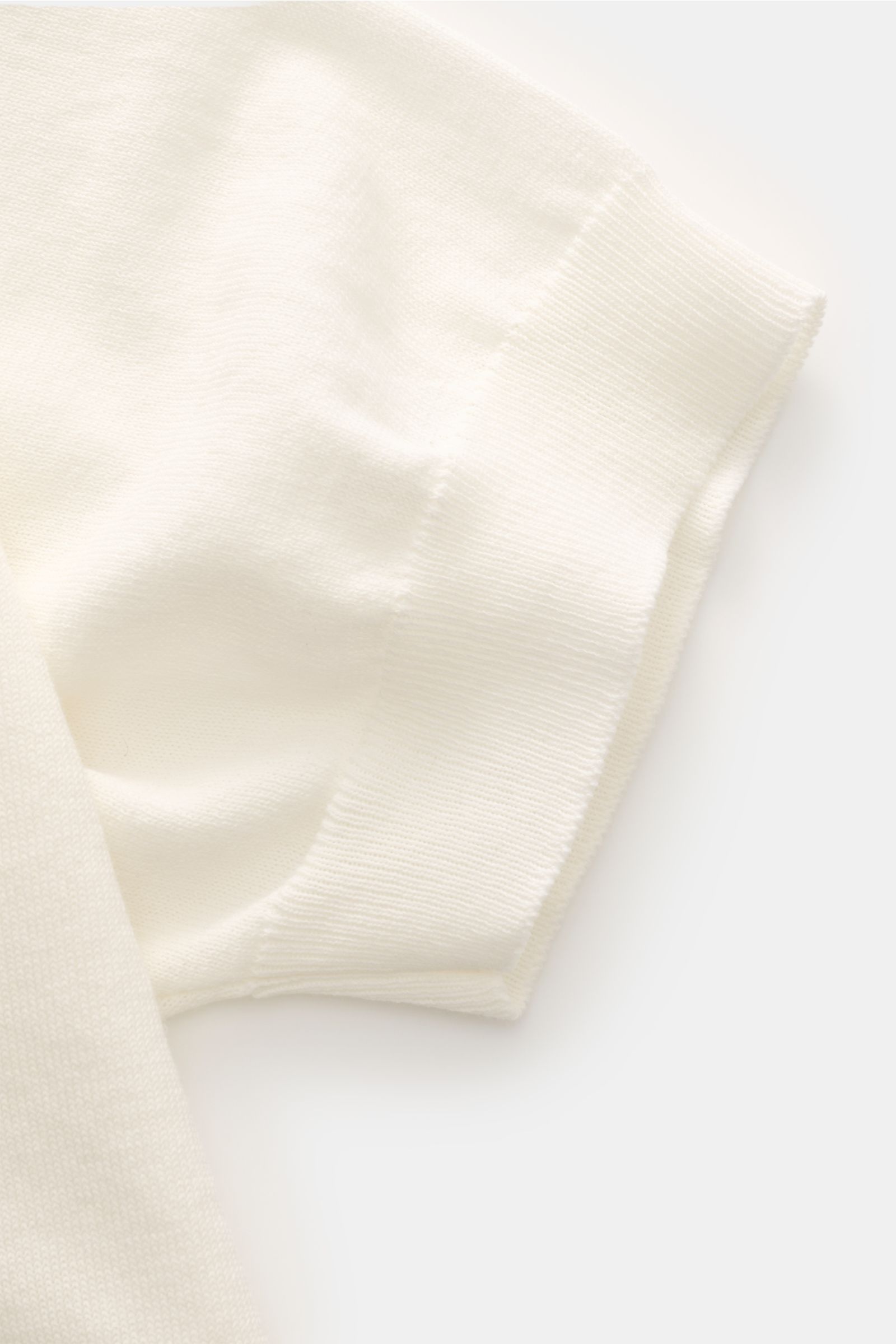 Piacenza 1733 Kurzarm-Strickpolo offwhite in Slim Fit, Detailaufnahme des feinen Baumwollstoffs und Rippbündchens am Ärmel.