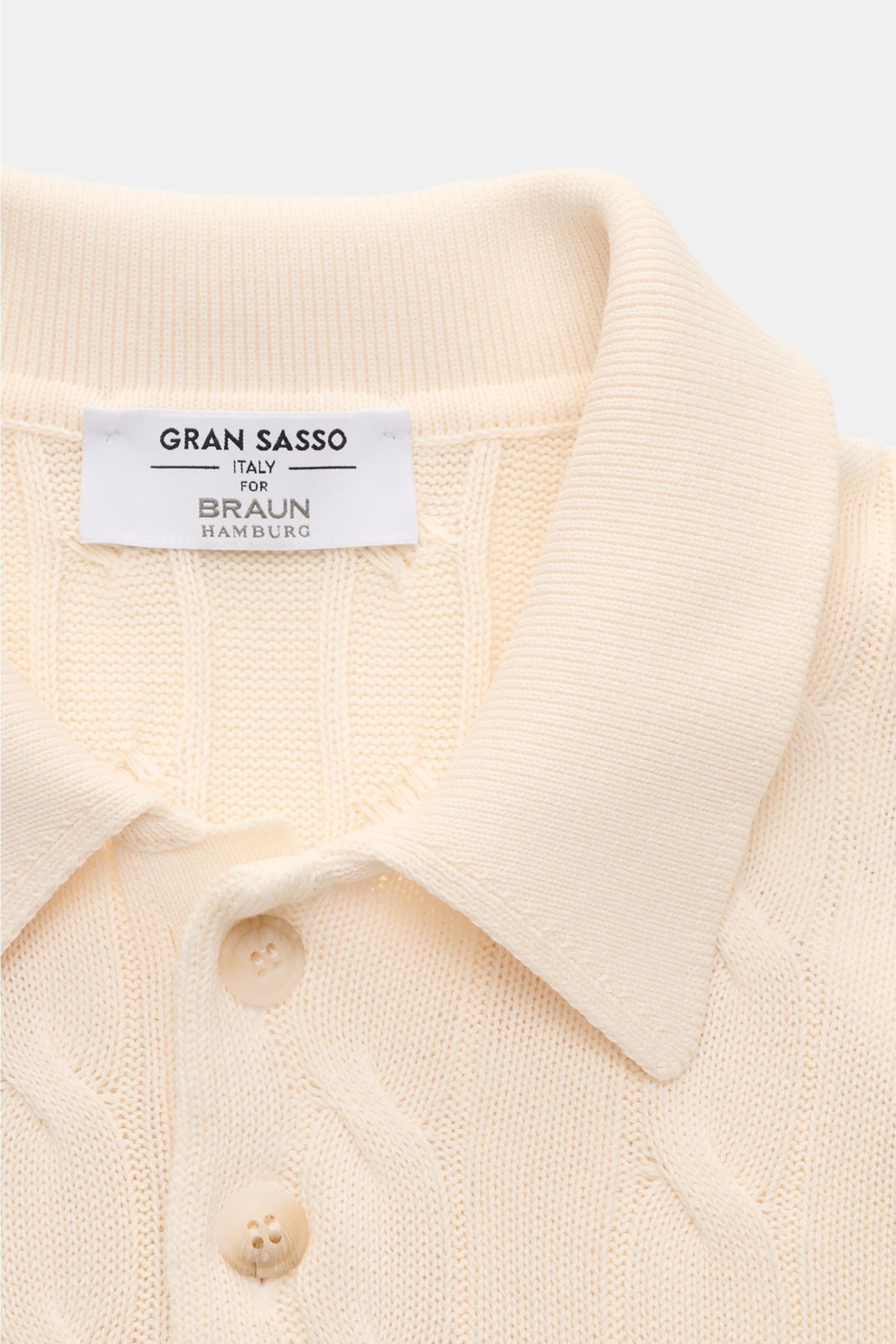 Close-up front view of the Gran Sasso Kurzarm-Strickpolo creme showing its classic polo collar, buttons, and cable knit pattern in soft cream color.

Description: Ideal für warme Tage: Das Kurzarm-Strickpolo von GRAN SASSO in exklusiver Fertigung für B