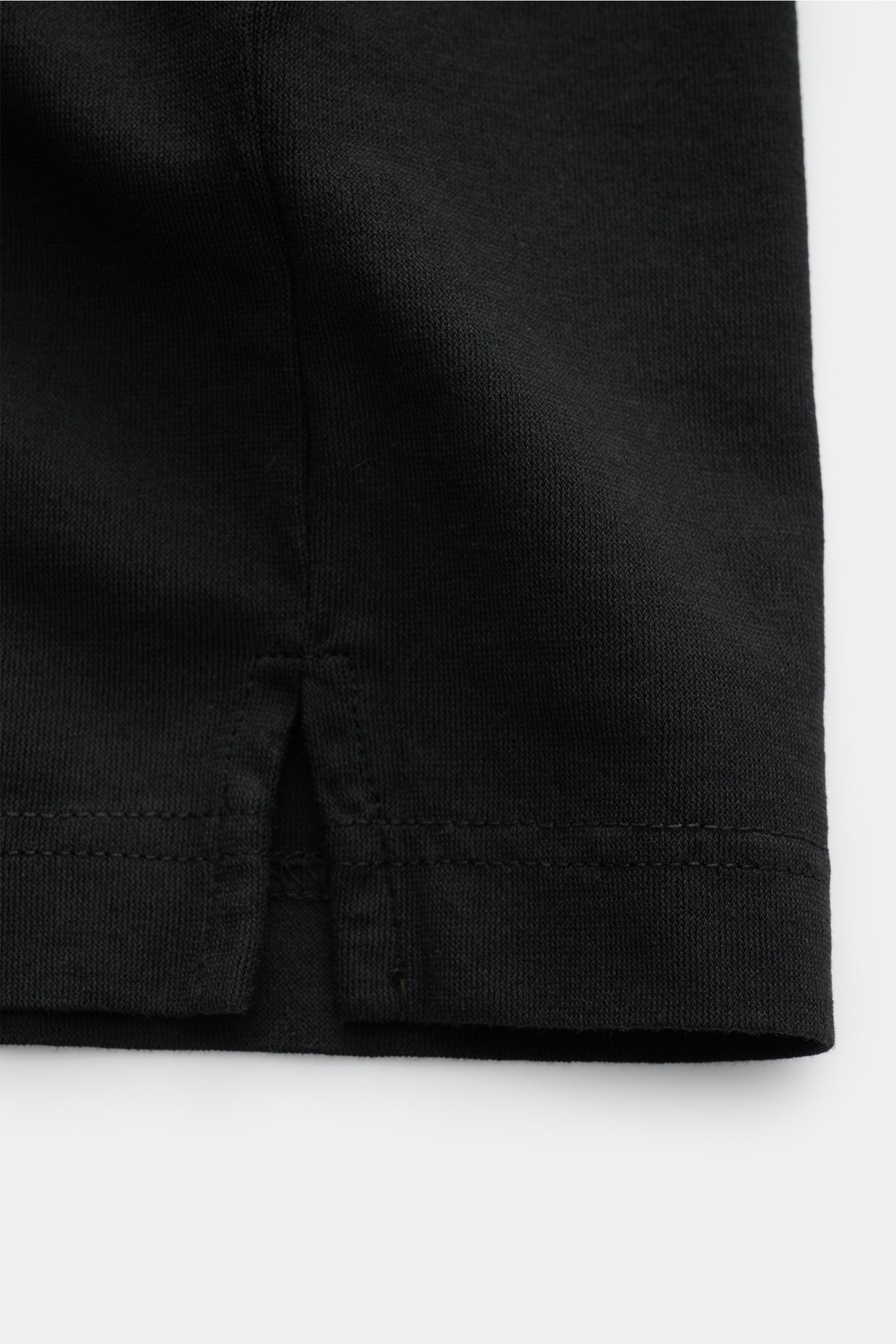 Close-up from above of the hem with side vents of the black BRAUN Hamburg Jersey polo shirt, showing fine cotton jersey texture.

Description: Sporty style for the new season: BRAUN HAMBURG has processed pure cotton into fine jersey to make this polo s