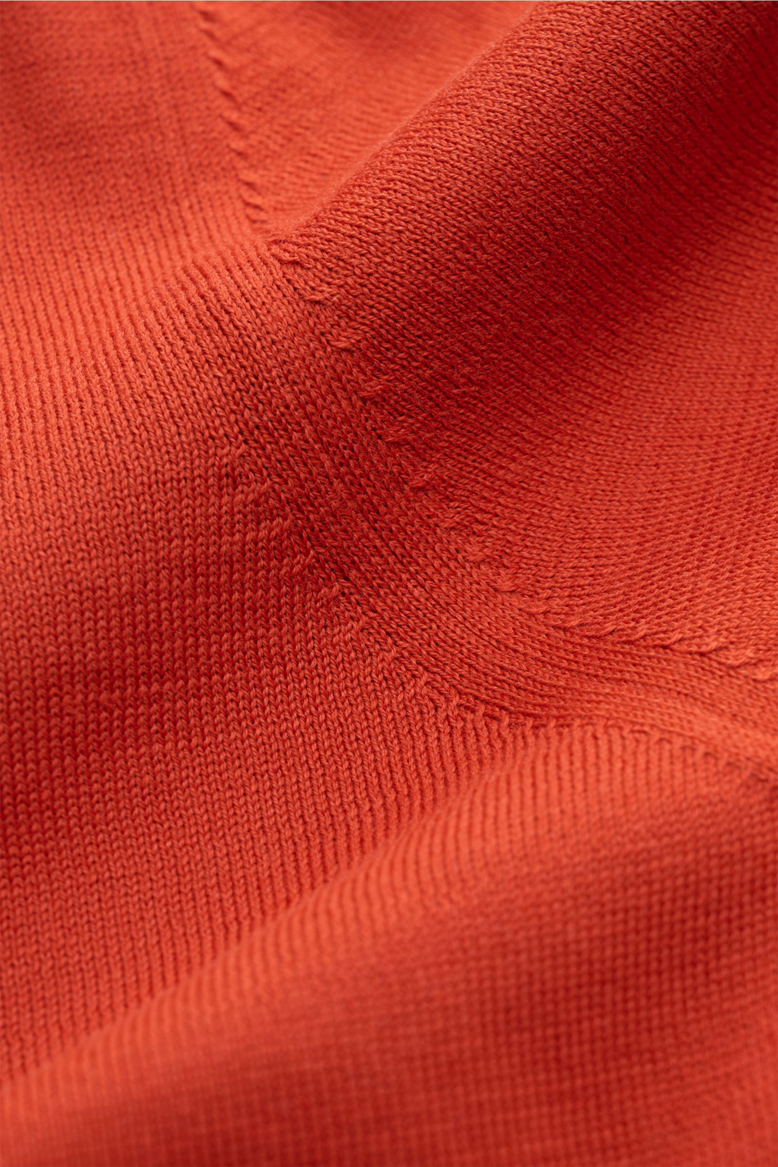 Nahaufnahme aus schräger Perspektive des feinen Strickbildes vom BRAUN Hamburg Kurzarm-Strickpolo orange aus weichem, reinem Baumwoll-Feinstrick.