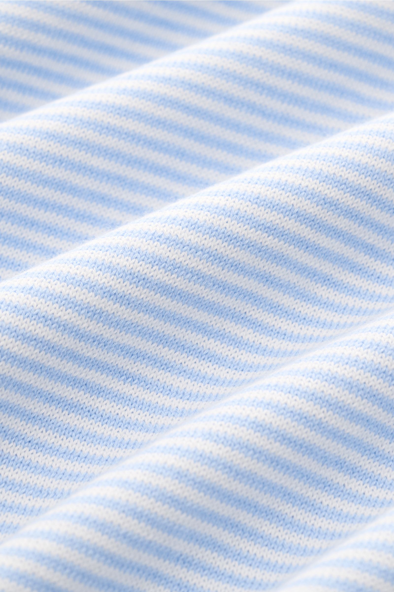 Close-up front view of the fine knit fabric of the BRAUN Hamburg Short sleeve knit polo light blue/white striped, showing soft cotton texture with slim fit, classic collar, open collar strip, and ribbed bands. Nautical style gets a modern interpretation: 