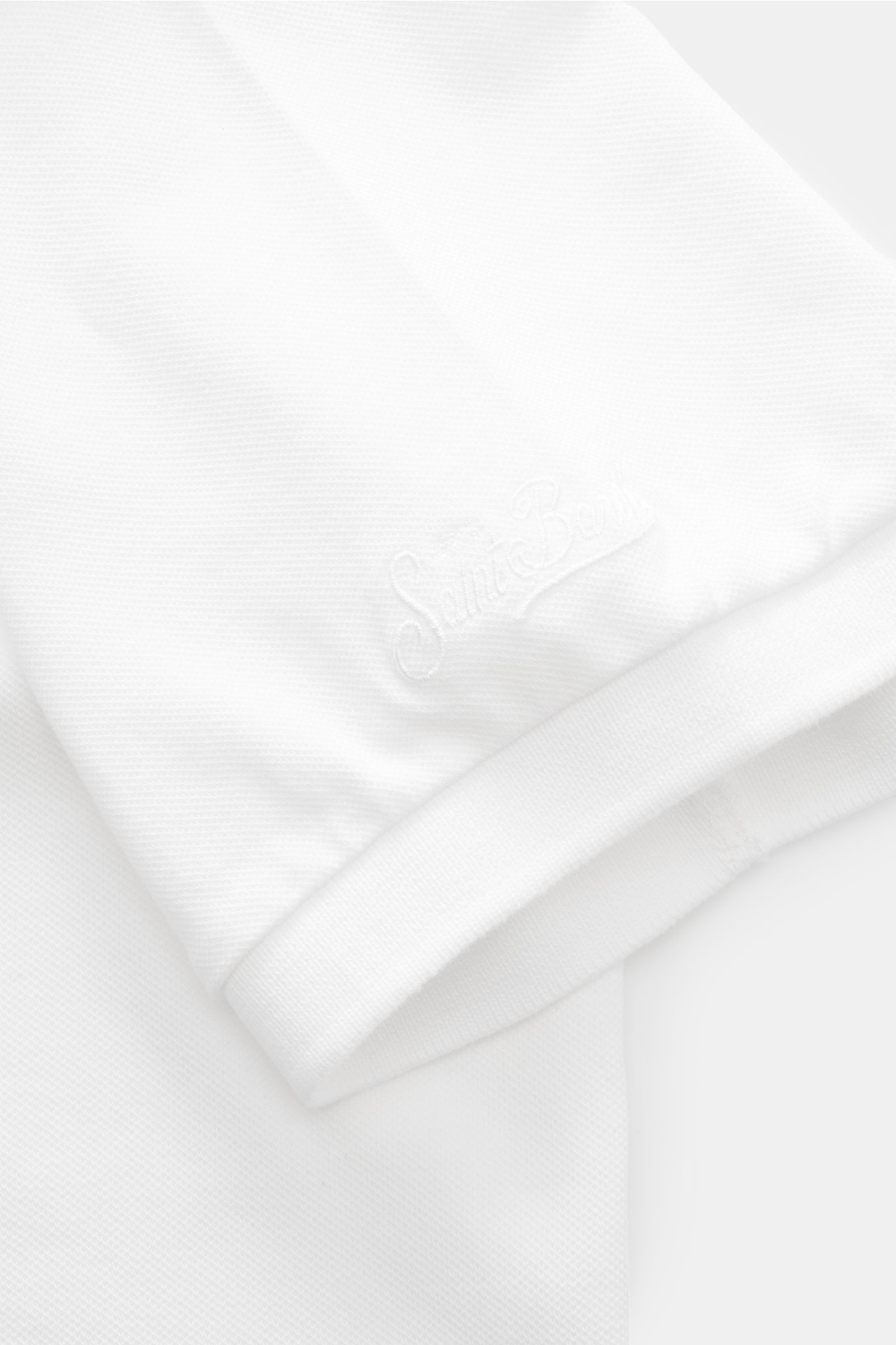 Nahaufnahme des MC2 Saint Barth Poloshirts 'Charles' weiß, fotografiert von schräg oben, mit elastischem Baumwoll-Piqué, weichem Griff, Rippbündchen und Logo-Stitching am Ärmel.