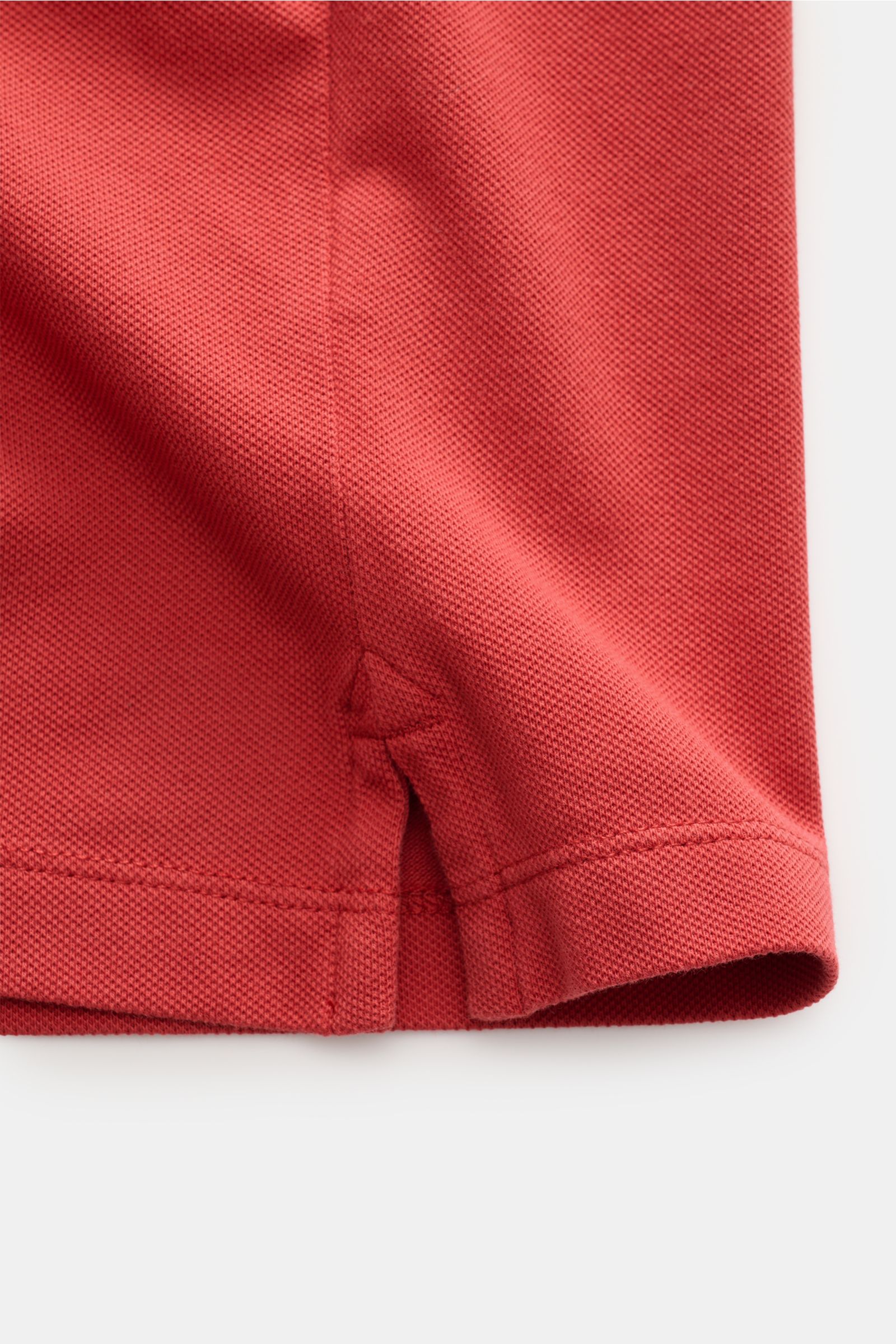 Close-up view of the sleeve hem of the MC2 Saint Barth Poloshirt 'Charles' rot, showing the textured red cotton piqué fabric, elastic quality, short side slits, and neat stitching from a side angle.