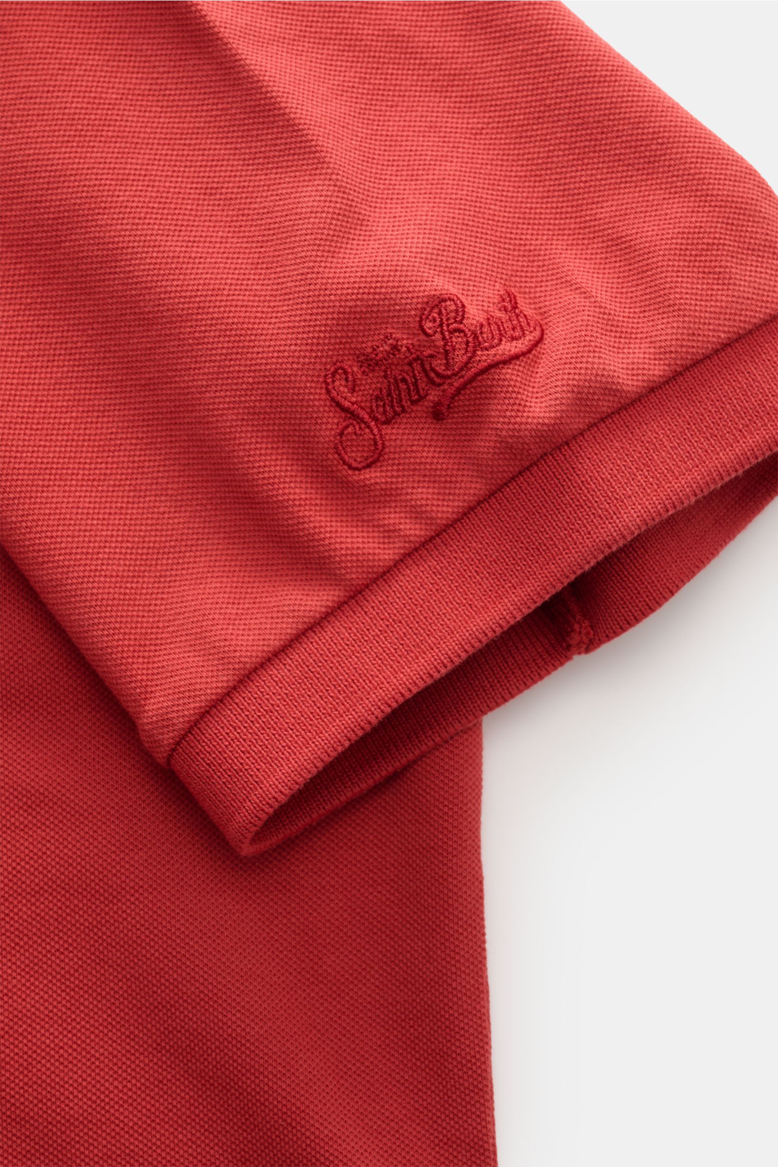 Close-up view of the sleeve hem and logo stitching of the MC2 Saint Barth Poloshirt 'Charles' rot in elastic red cotton piqué fabric, showing the soft texture and comfortable ribbed cuff. 