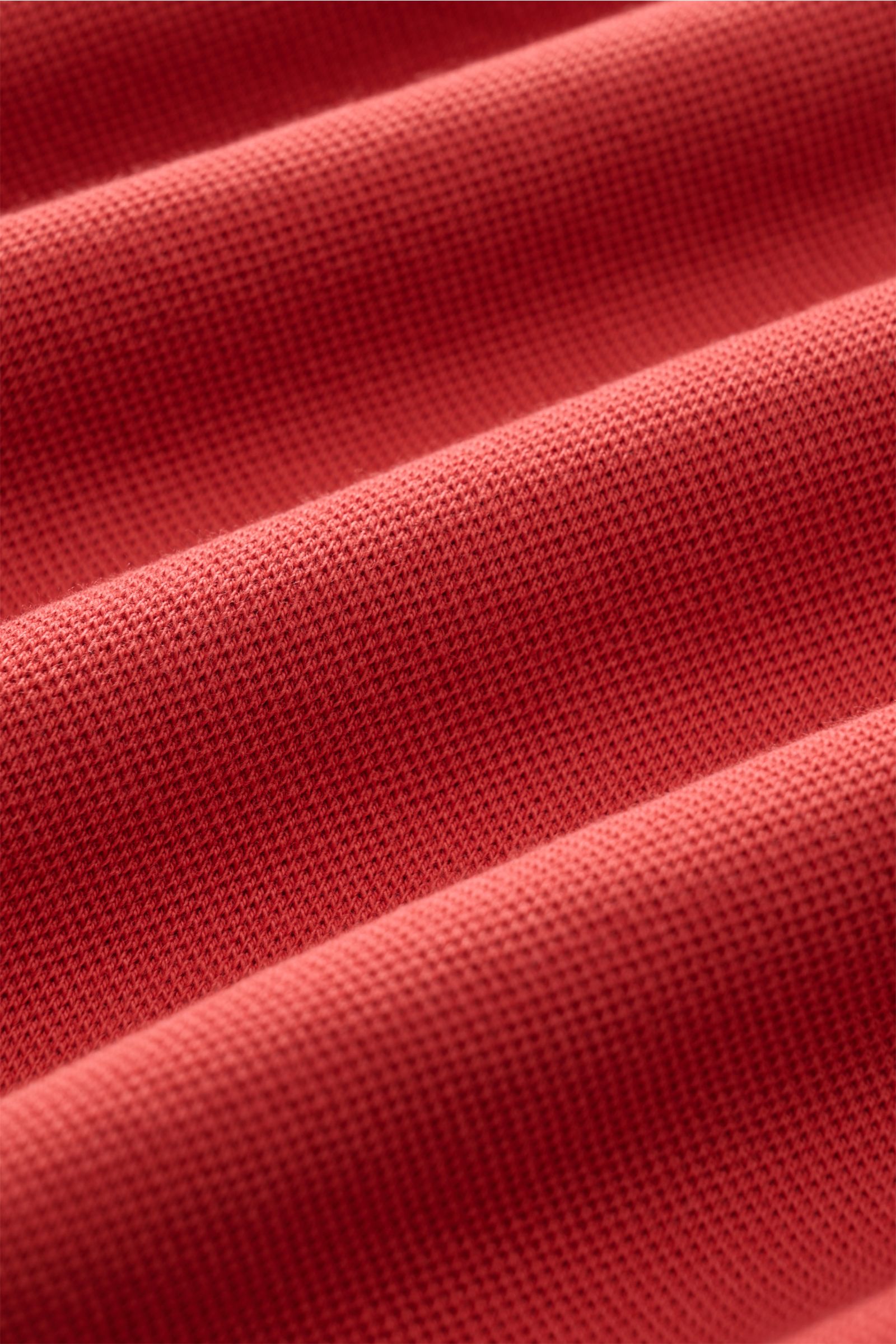 Close-up image of the fabric texture of the MC2 Saint Barth Poloshirt 'Charles' rot, showing red elastic cotton piqué material with soft touch, photographed from a side angle highlighting the fabric's weave and surface details. 