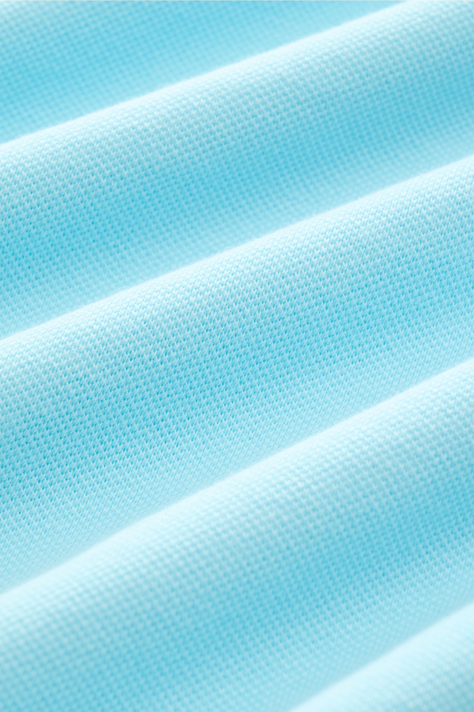 Close-up image showing the fabric texture of the MC2 Saint Barth Poloshirt 'Charles' türkis, photographed from a front angle, highlighting the elastic, soft cotton piqué material with a turquoise color. This fabric features a slim fit, typical polo collar