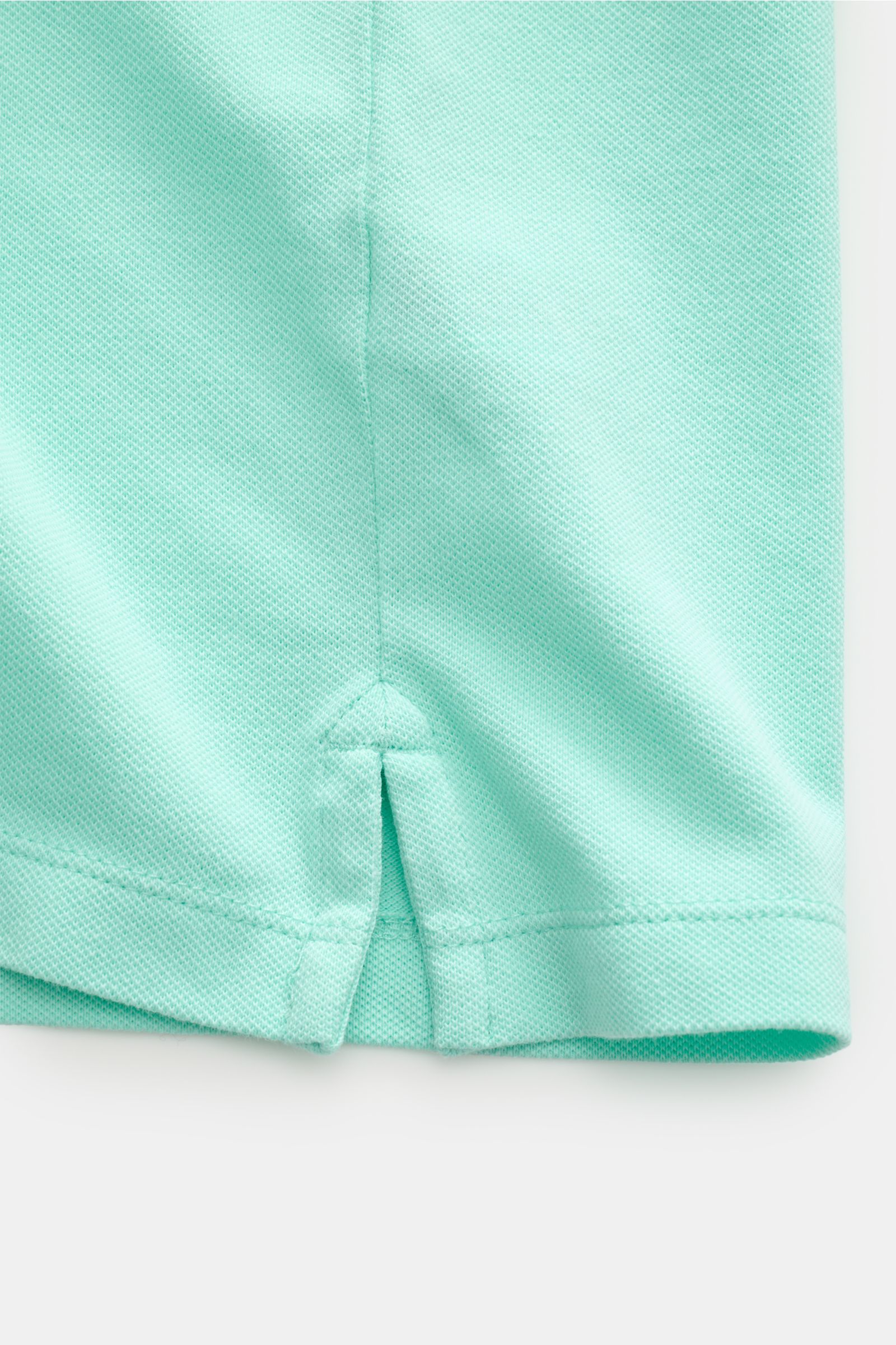 Close-up front view of the hem and side slit of the MC2 Saint Barth Poloshirt 'Charles' mintgrün, made of elastic, soft cotton piqué with ribbed cuffs and logo stitching, showing the short hem slit detail.