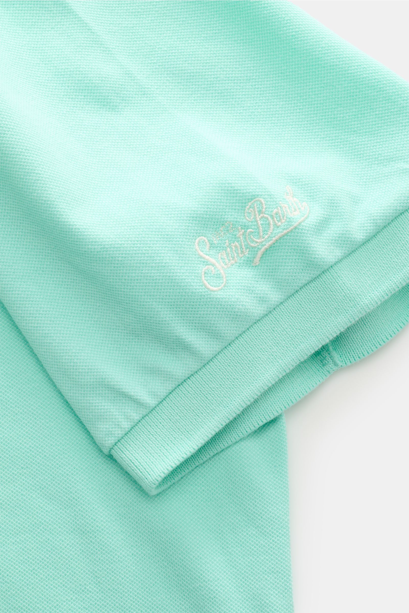 MC2 Saint Barth Poloshirt 'Charles' mintgrün close-up from above showing elastic cotton piqué fabric, soft texture, ribbed cuffs, logo stitching, and hem slits.