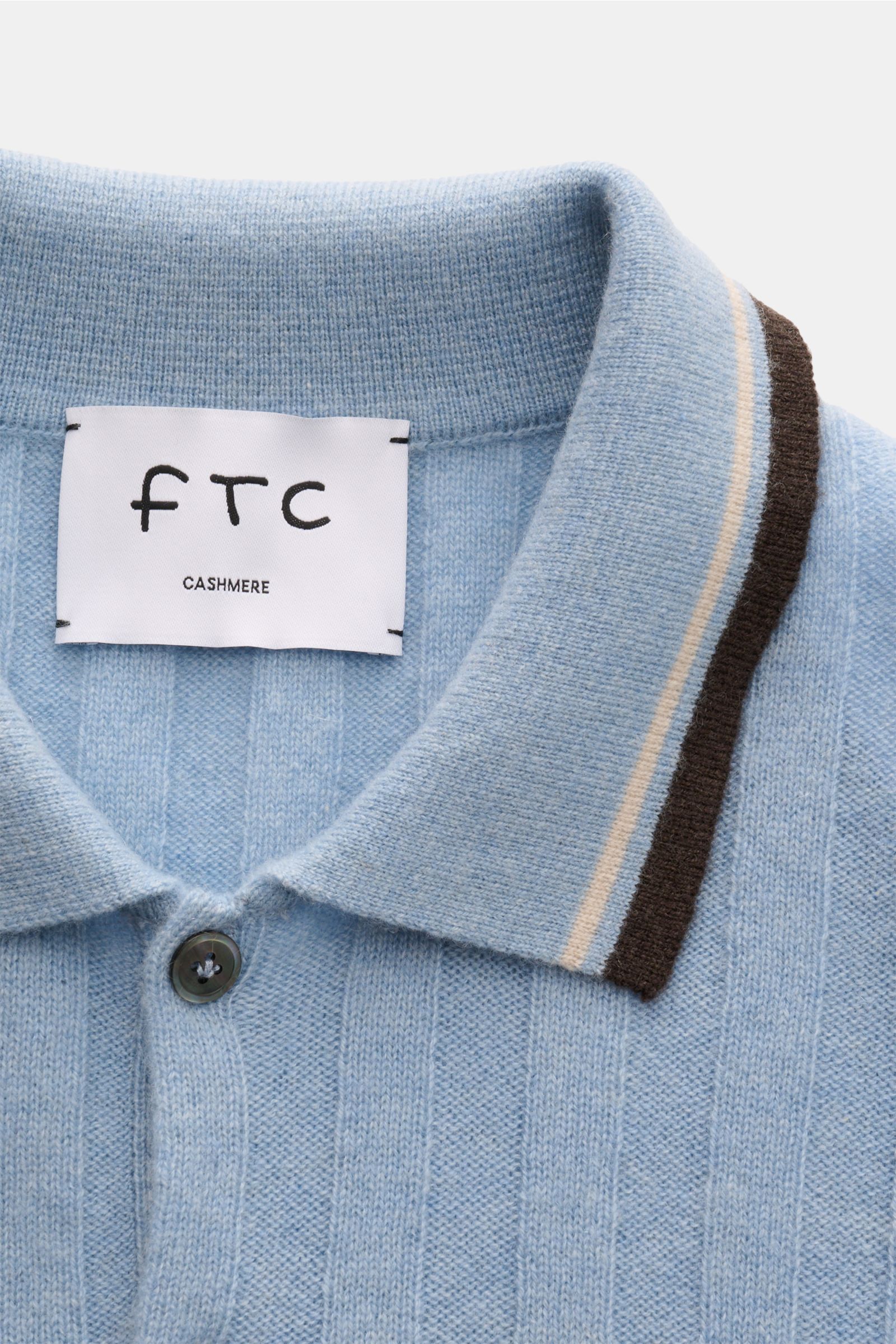 Nahaufnahme des hellblauen FTC Cashmere Kurzarm-Strickpolos mit breitem Rippstrick, Polokragen und farblich abgesetzten Streifen, von oben fotografiert.
