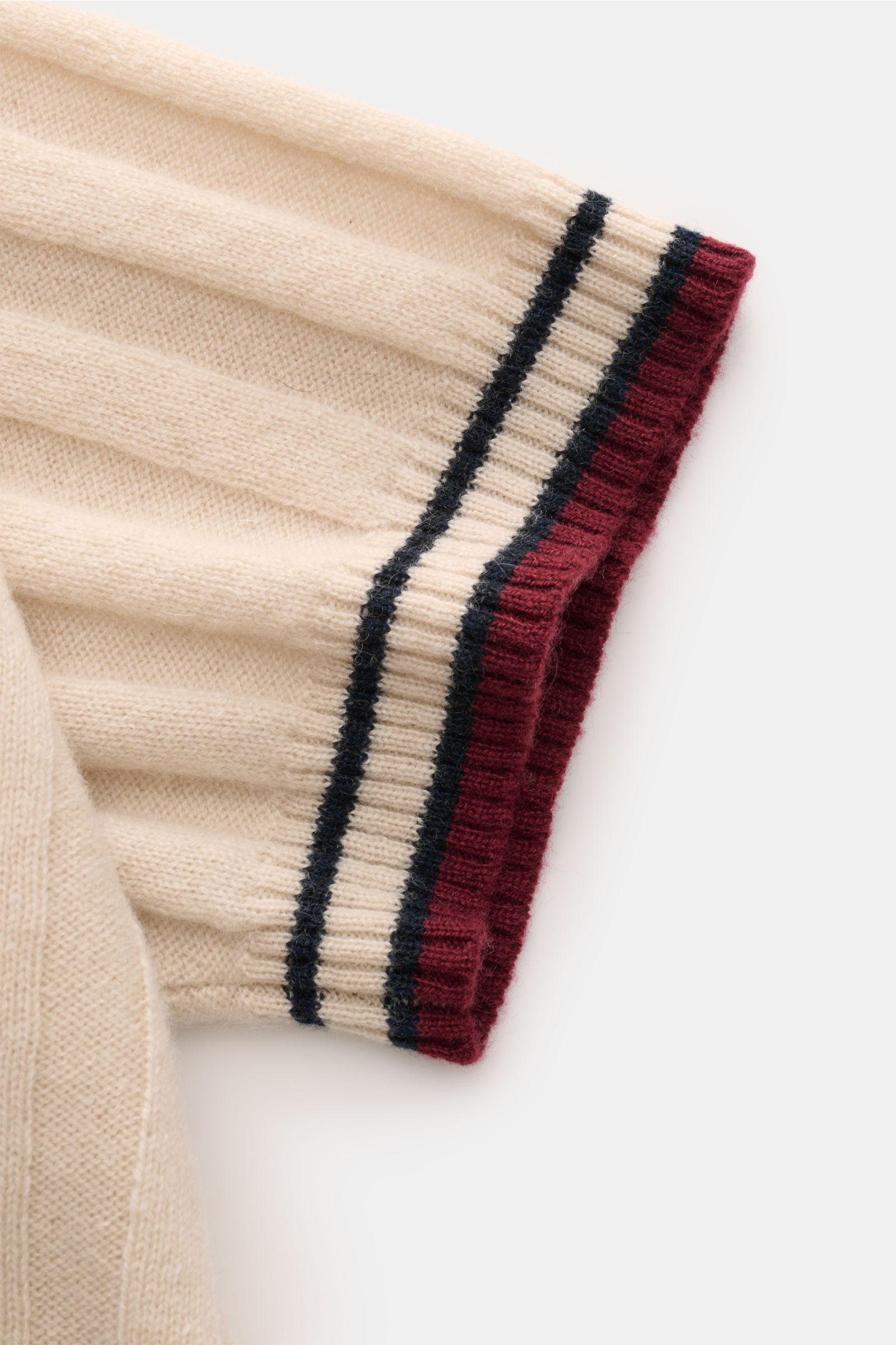 Nahaufnahme des Ärmels vom FTC Cashmere Kurzarm-Strickpolo beige, breites Rippstrick-Design mit farblich abgesetzten Streifen in Bordeaux und Dunkelblau.