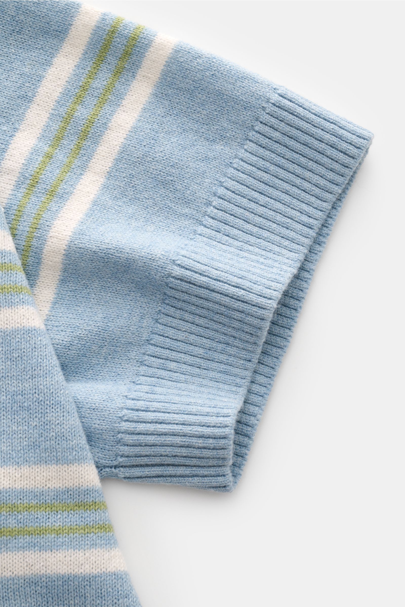 Nahaufnahme des Ärmels vom FTC Kurzarm-Strickpolo hellblau/weiß/grün gestreift, Slim Fit mit feinem Strickbild, Polokragen, Zwei-Knopf-Leiste, flexible Rippbündchen, edler Baumwoll-, SeaCell- und Cashmere-Mix, fotografiert von oben.