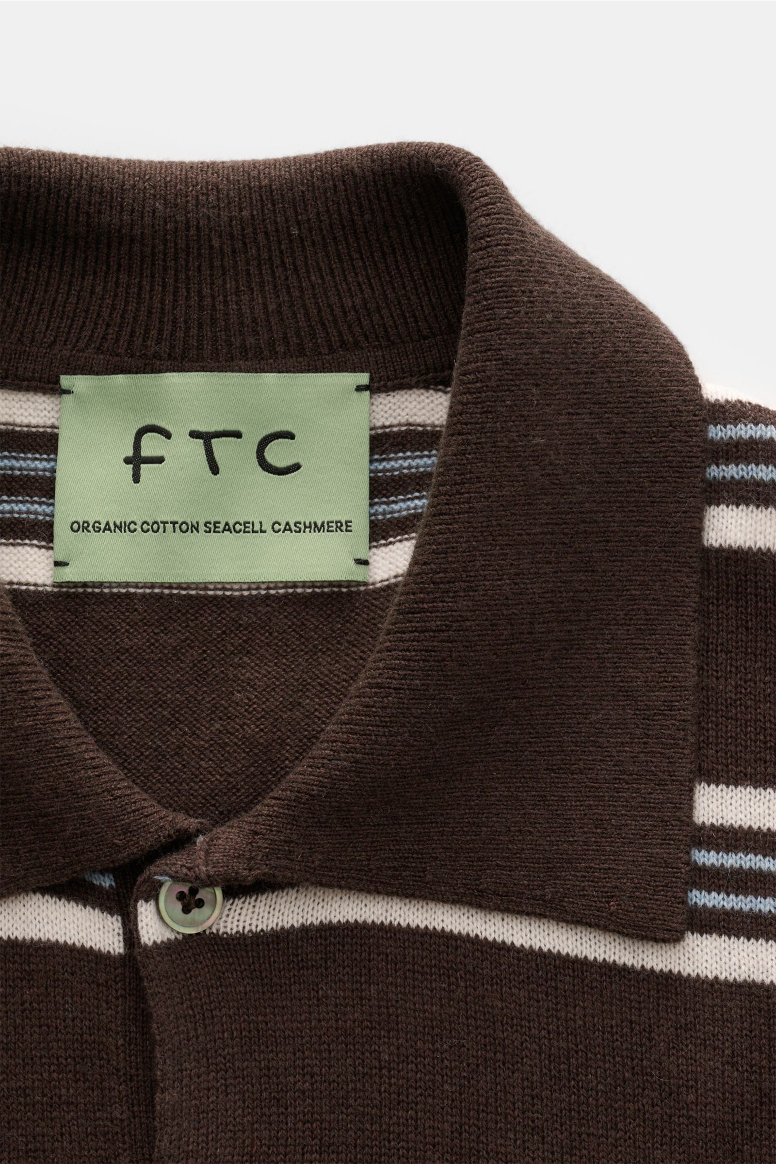Nahaufnahme des FTC Kurzarm-Strickpolo dunkelbraun/creme/hellblau gestreift mit Polokragen, Zwei-Knopf-Leiste und feinem Strickbild.