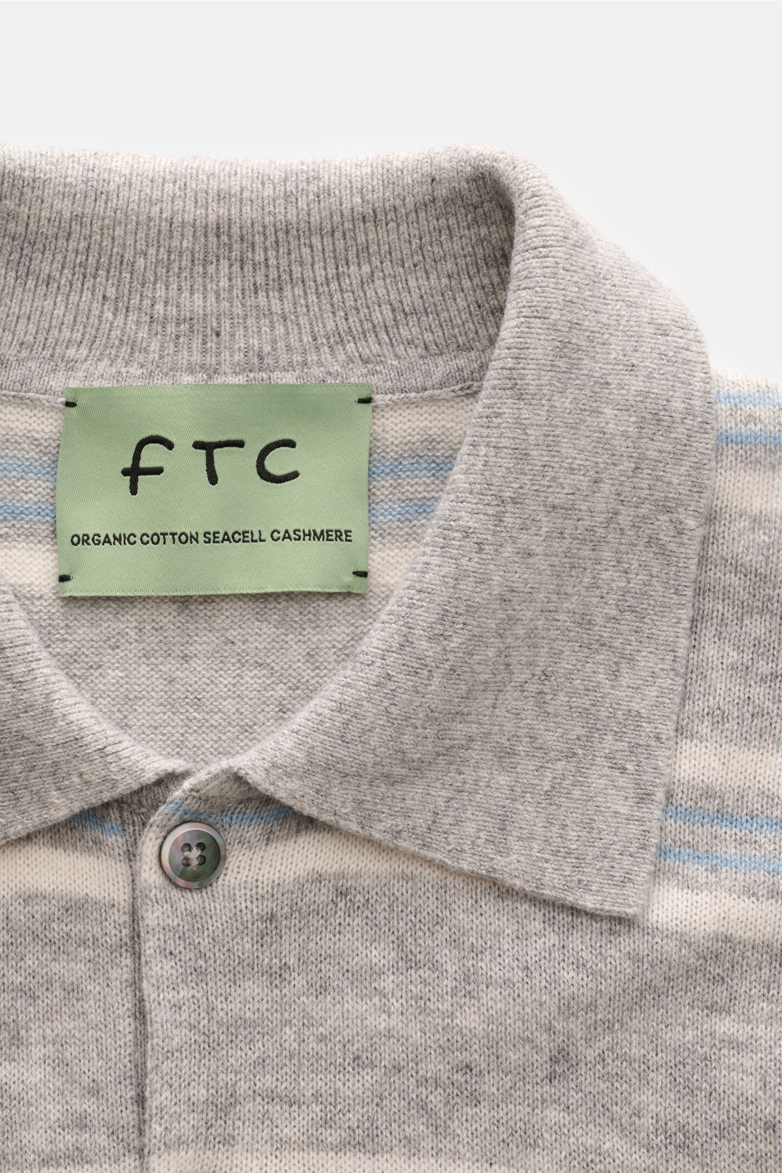 Nahaufnahme von FTC Kurzarm-Strickpolo grau/hellblau/weiß gestreift mit Polokragen, Zwei-Knopf-Leiste, aus Baumwolle, SeaCell und Cashmere.