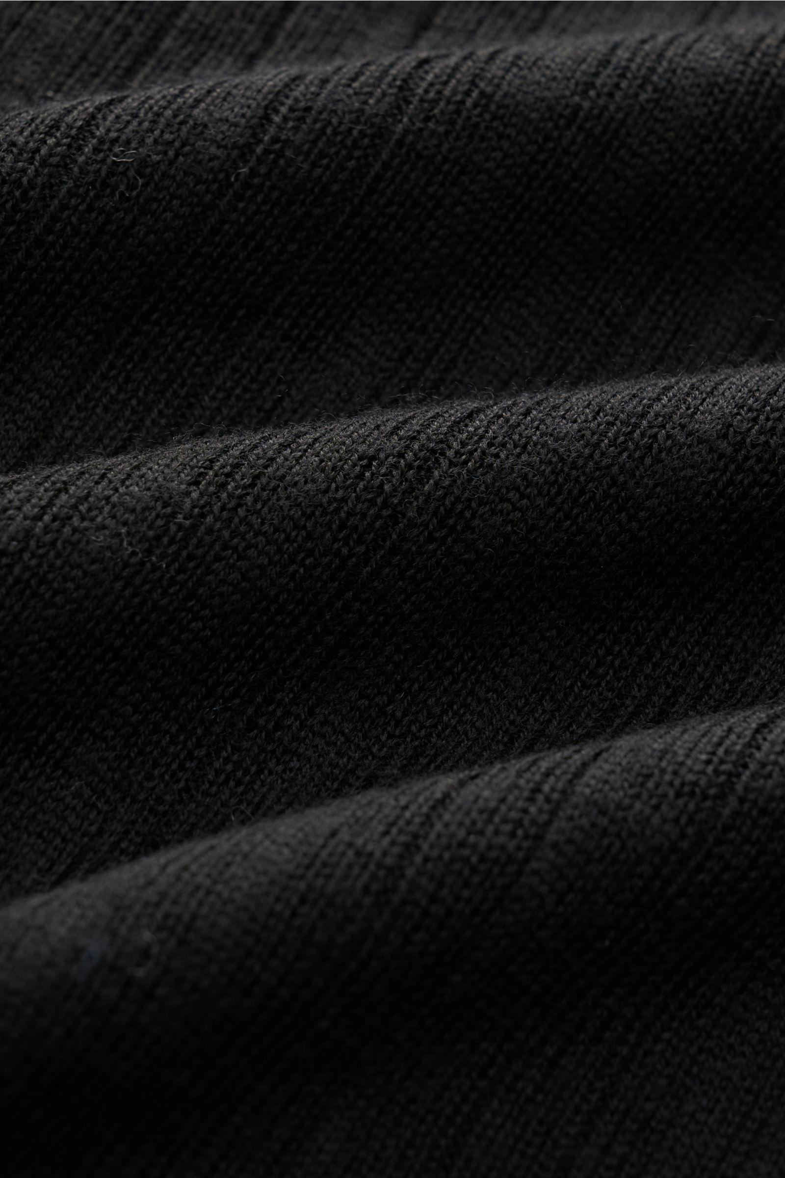 Black fine textured knit fabric shown up close from a flat lay perspective, highlighting the soft merino wool texture of the Kiefermann Merino short sleeve knit polo 'Bortiso' black.

An elegant styling piece: For a holiday dinner or a walk on the prom