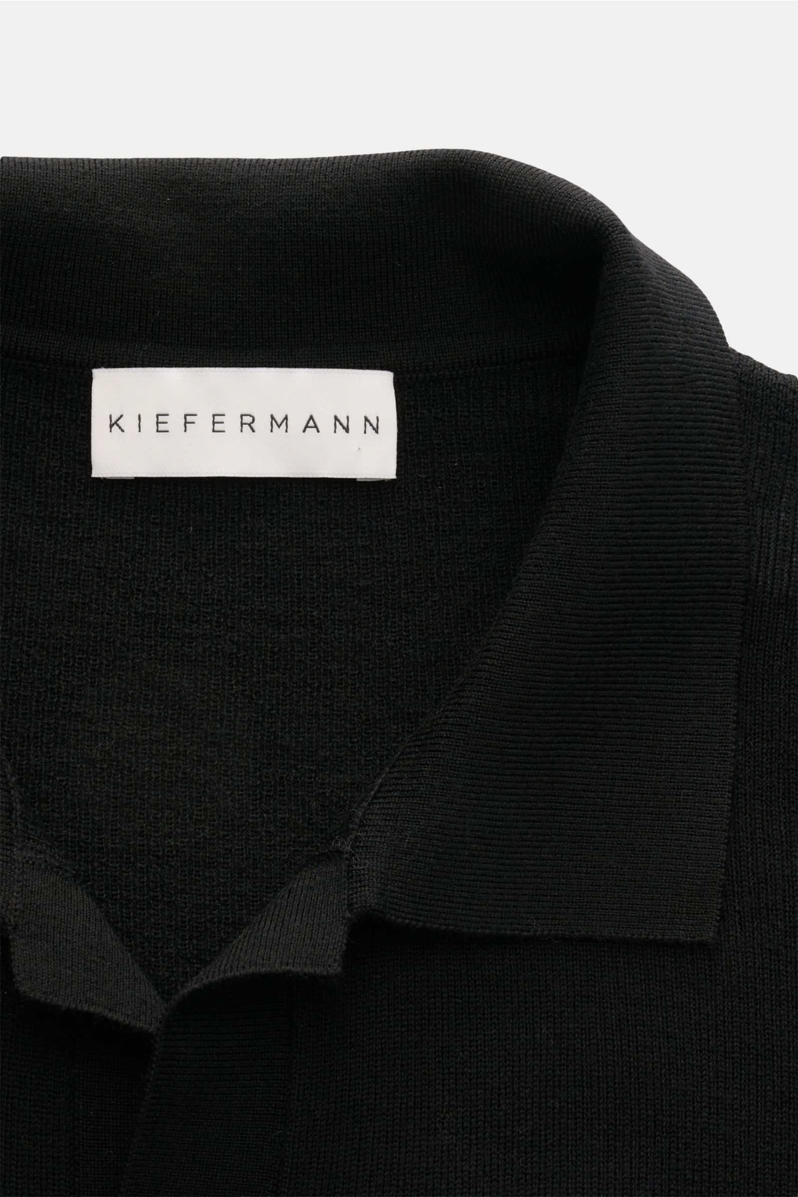 Close-up front view of Kiefermann Merino short sleeve knit polo 'Luras' black showing classic collar, open collar strip, and fine rib knit texture.

Sporty and timeless: This short sleeve knit polo by KIEFERMANN in high-quality merino wool has a casual
