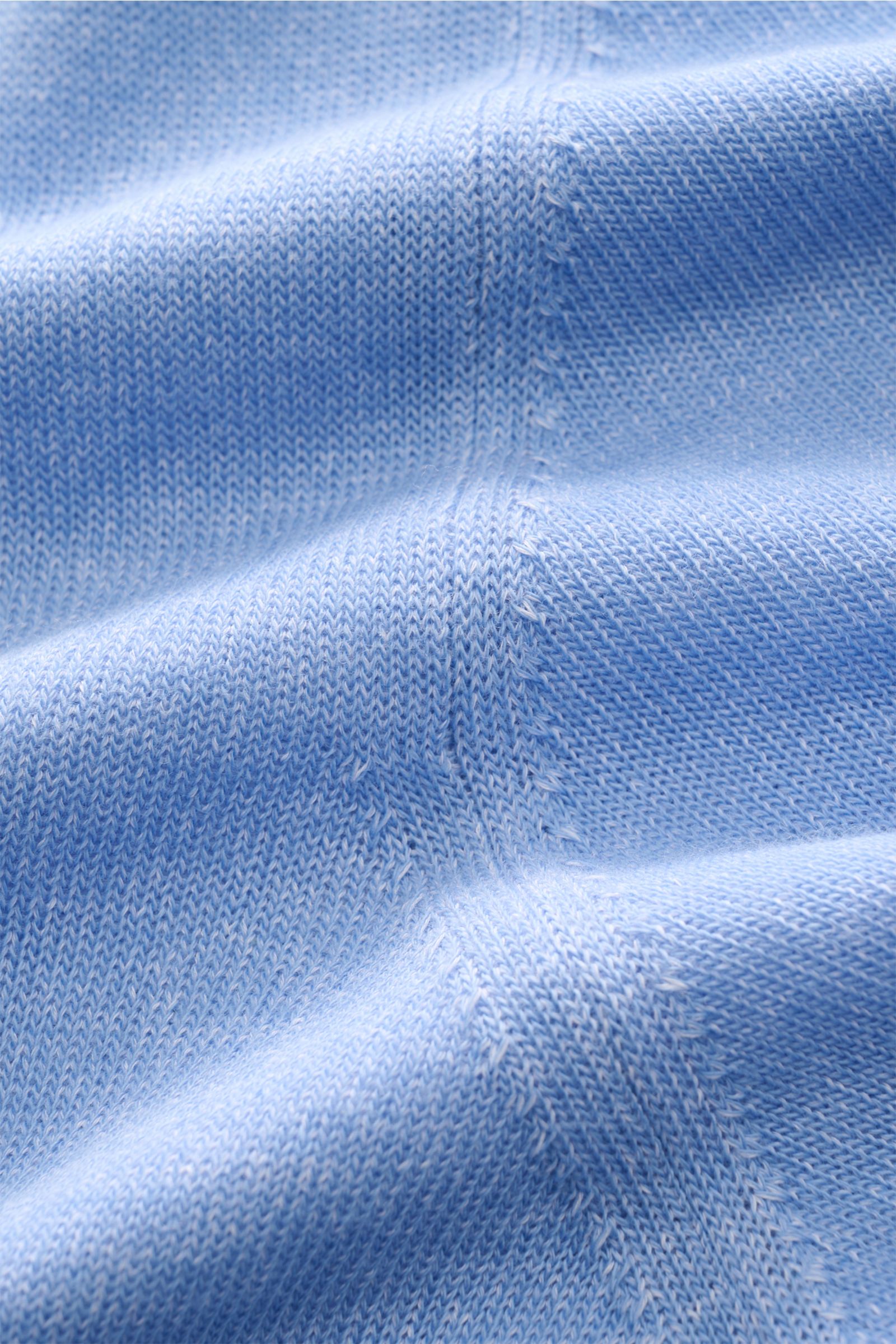 Close-up view of the light blue melange knit fabric of the Moorer Kurzarm-Strickpolo 'Coty' showing fine stitching and soft texture. Mehr als ein Basic: Für das Strickpolo 'Coty' kombiniert MOORER gekämmte Baumwolle mit Baumwoll-Crêpe und schafft so spann