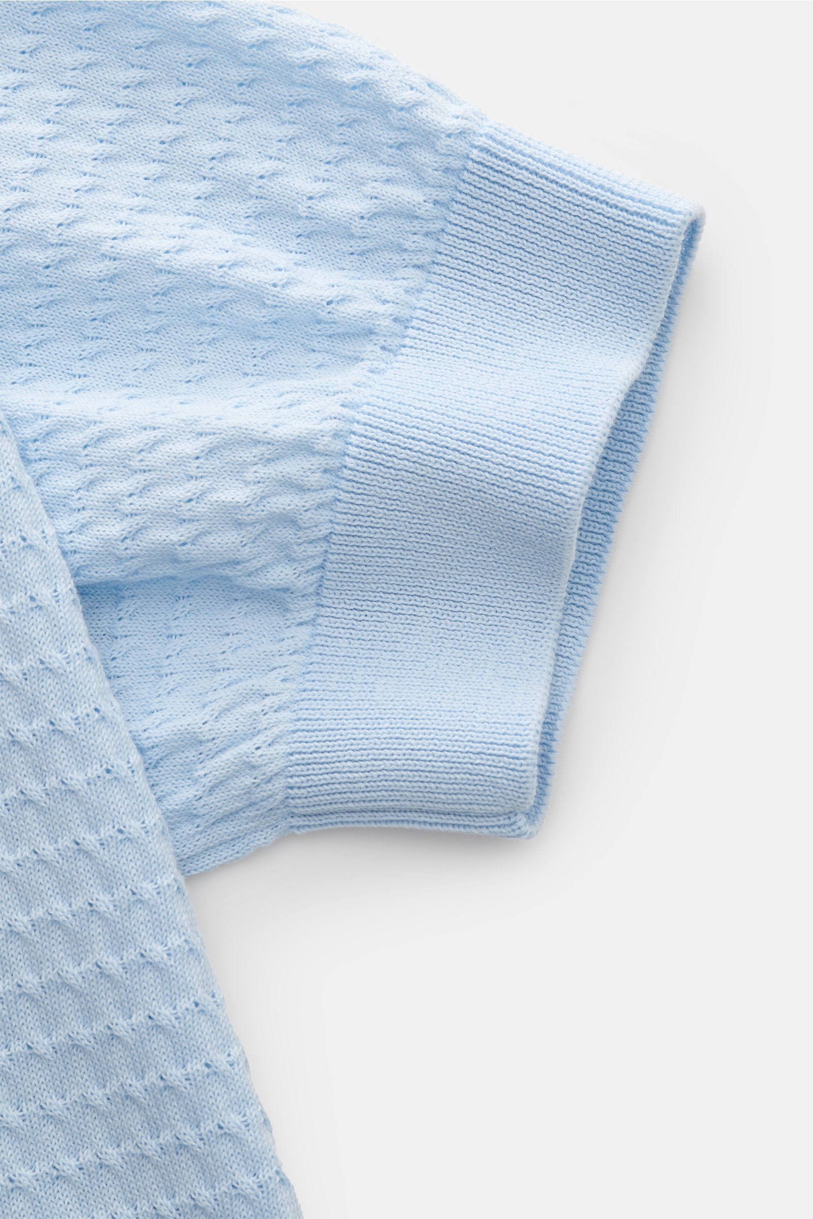 Close-up side view of the pastel blue Filippo de Laurentiis Kurzarm-Strickpolo pastellblau sleeve showing fine structure knit and ribbed cuff. Darf es etwas neues sein? FILIPPO DE LAURENTIIS präsentiert dieses Strickpolo aus luftiger Baumwolle mit edle