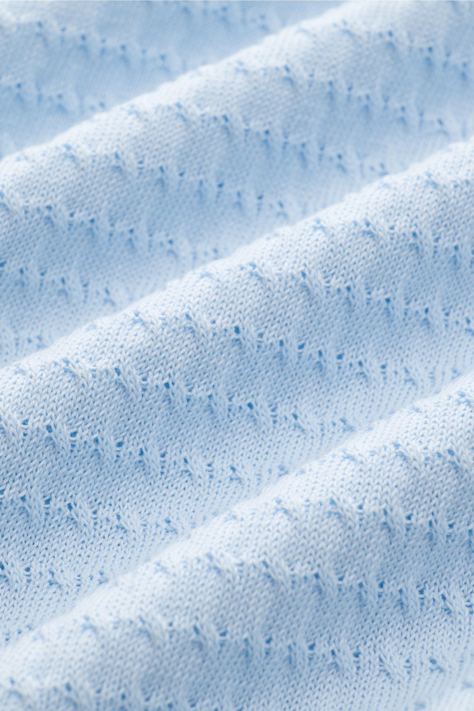 Close-up view of light blue fabric texture of Filippo de Laurentiis Kurzarm-Strickpolo pastellblau, showing fine structure knitting and soft cotton. Darf es etwas neues sein? FILIPPO DE LAURENTIIS präsentiert dieses Strickpolo aus luftiger Baumwolle mi