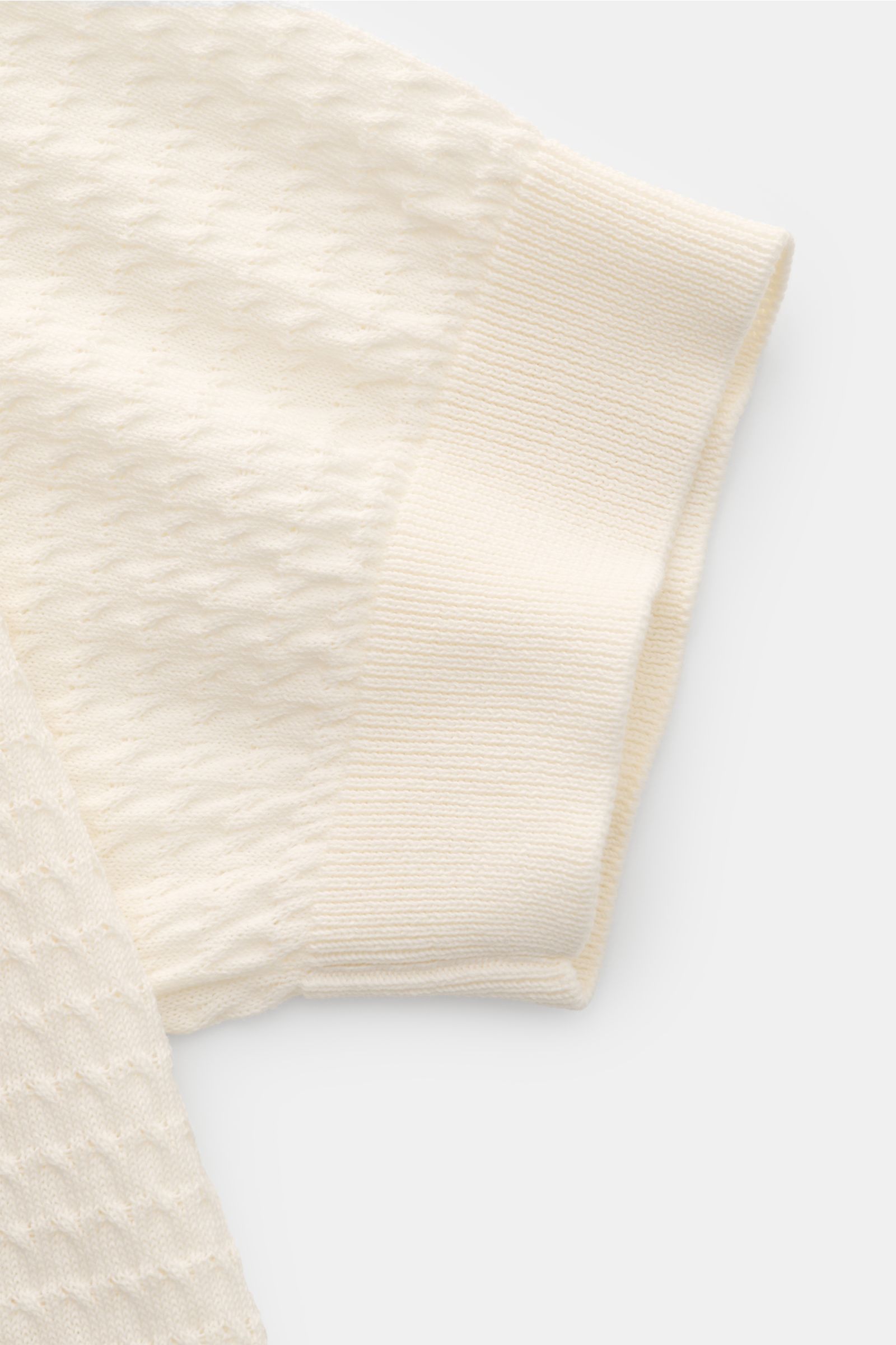 Close-up top view of Filippo de Laurentiis Kurzarm-Strickpolo offwhite sleeve showing fine textured knit and ribbed cuff.

Description: Darf es etwas neues sein? FILIPPO DE LAURENTIIS präsentiert dieses Strickpolo aus luftiger Baumwolle mit edlem, fein