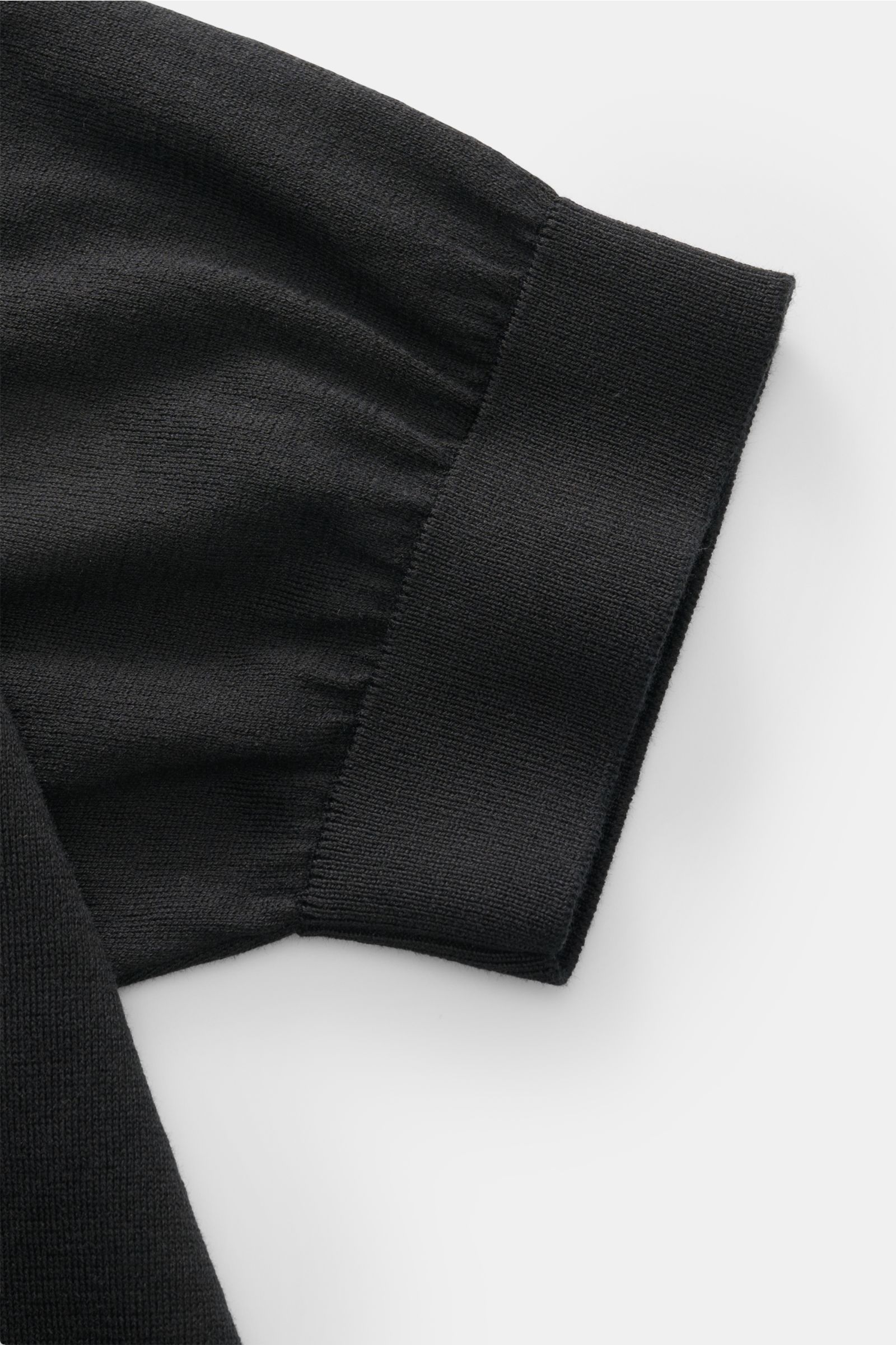 Close-up side view of the sleeve cuff of the Filippo de Laurentiis Kurzarm-Strickpolo schwarz, featuring fine ribbed cuffs and soft black cotton knit fabric. A perfect summer basic: the short-sleeve knit polo by FILIPPO DE LAURENTIIS impresses with a soft