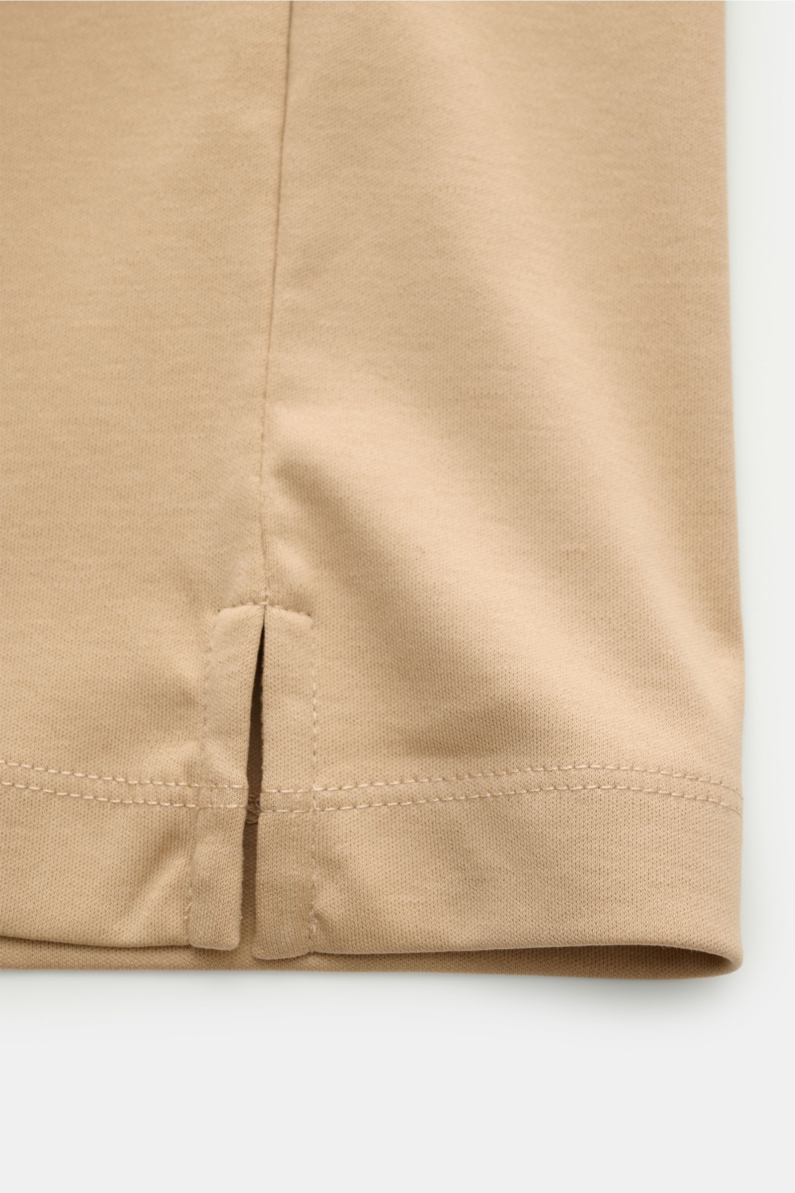 Nahaufnahme des Saums mit kurzer Saumschlitze des beigefarbenen Aurélien Jersey Poloshirts, gefertigt aus ägyptischer Baumwolle in Slim Fit.