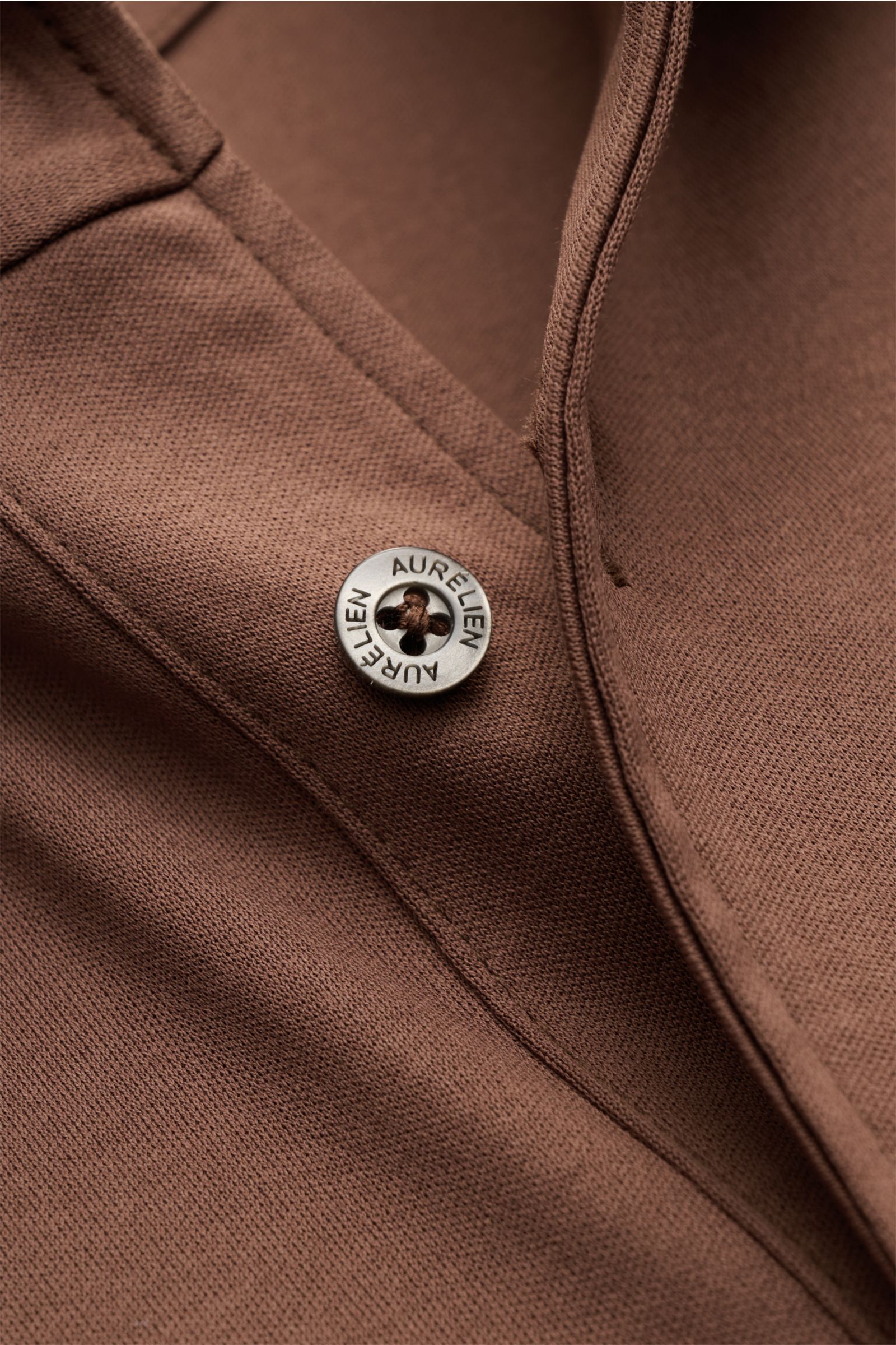 Nahaufnahme des Aurélien Jersey-Poloshirt braun von oben, zeigt Slim Fit, konfektionierten Polokragen, Drei-Knopf-Leiste, reine Baumwolle mit kühlem Griff.