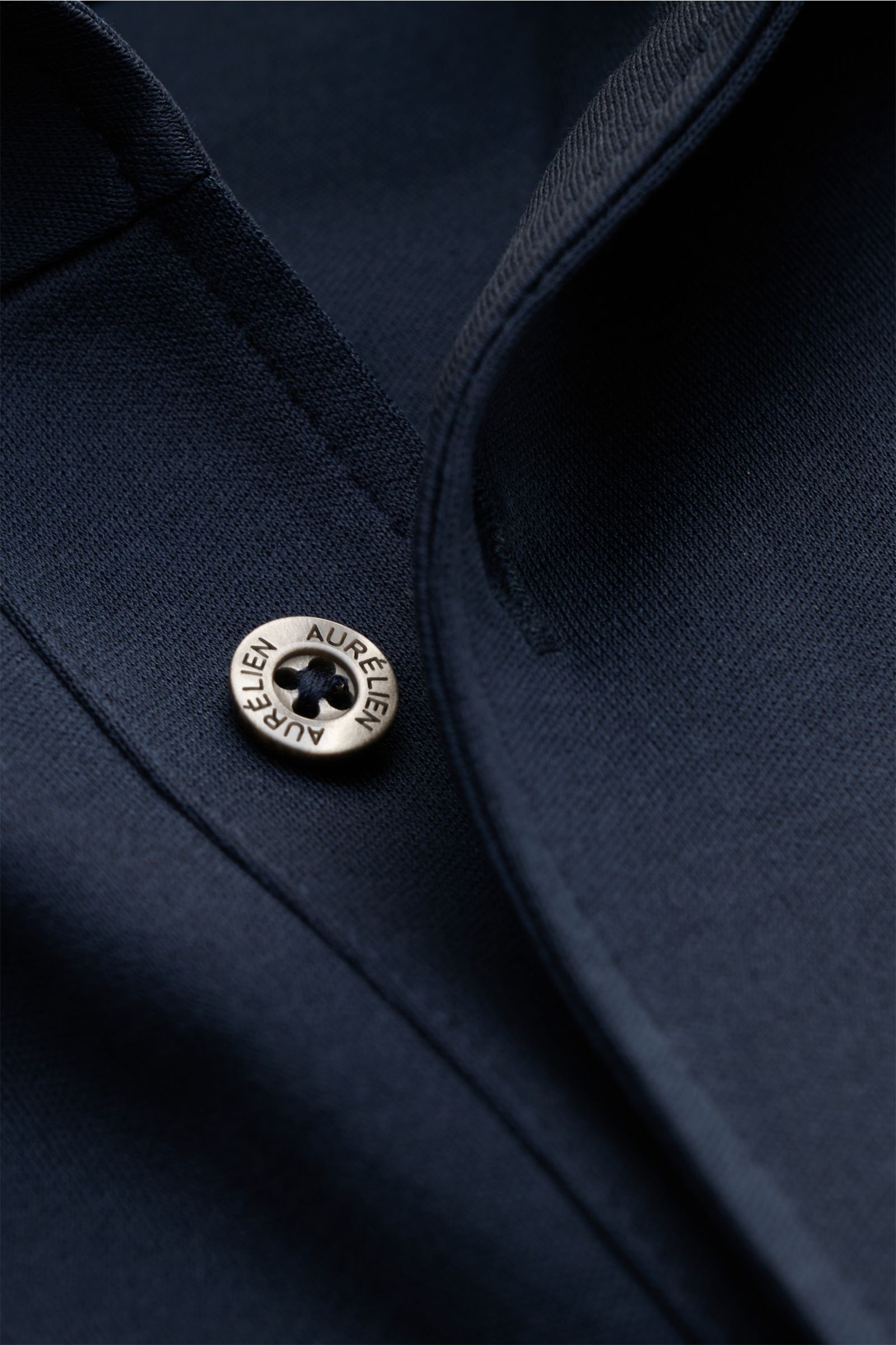 Close-up image of the Aurélien Jersey-Poloshirt navy showing the slim fit, pure cotton fabric, smooth, cool touch, tailored polo collar, and three-button placket from a top-down angle.