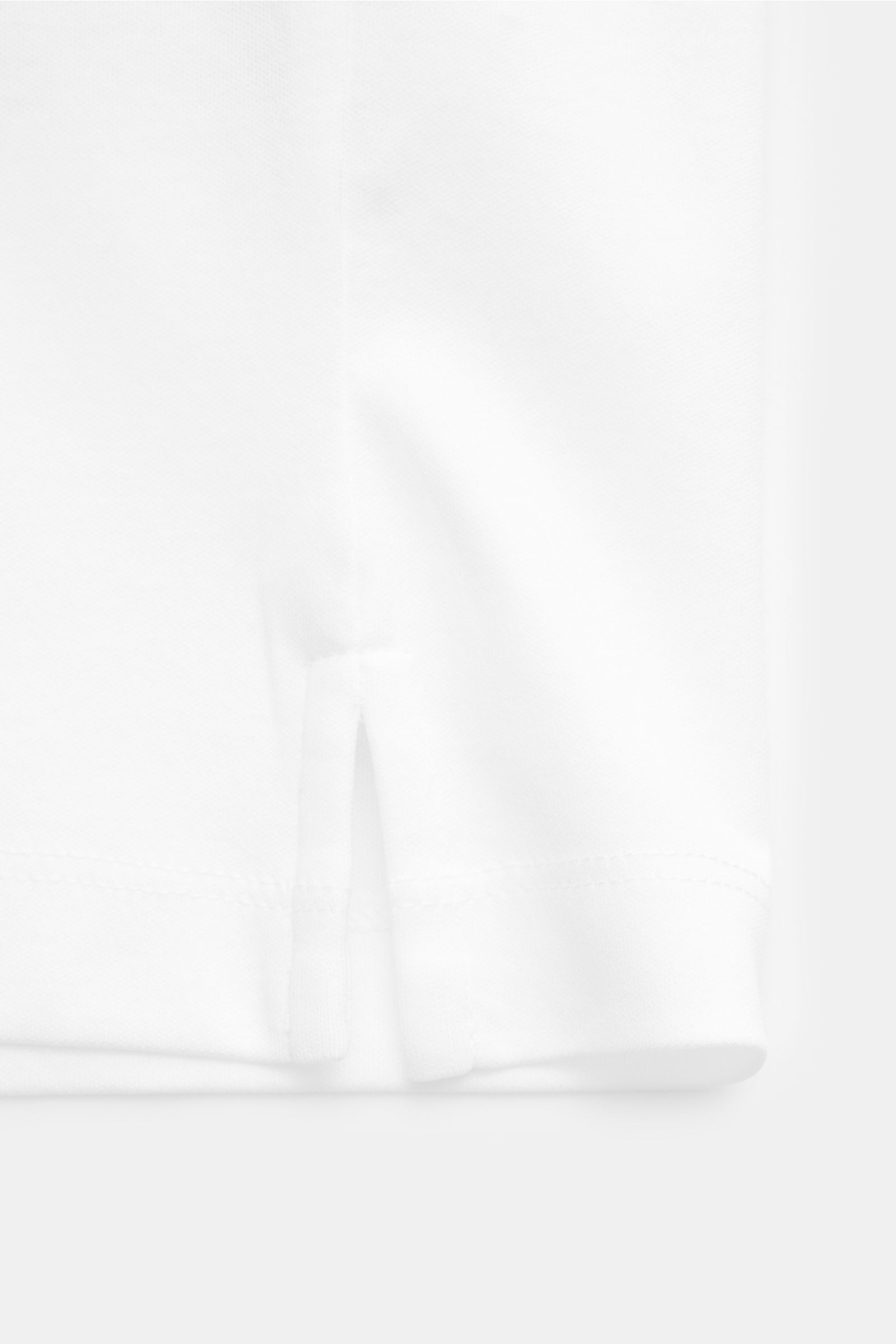 Close-up side view of the hem with short side slits of the Aurélien Jersey-Poloshirt weiß, a slim fit, pure cotton polo shirt with a smooth, cool touch. Vielseitiges Basic für den Frühling und Sommer: Das Jersey-Poloshirt von AURÉLIEN verbindet langstapli