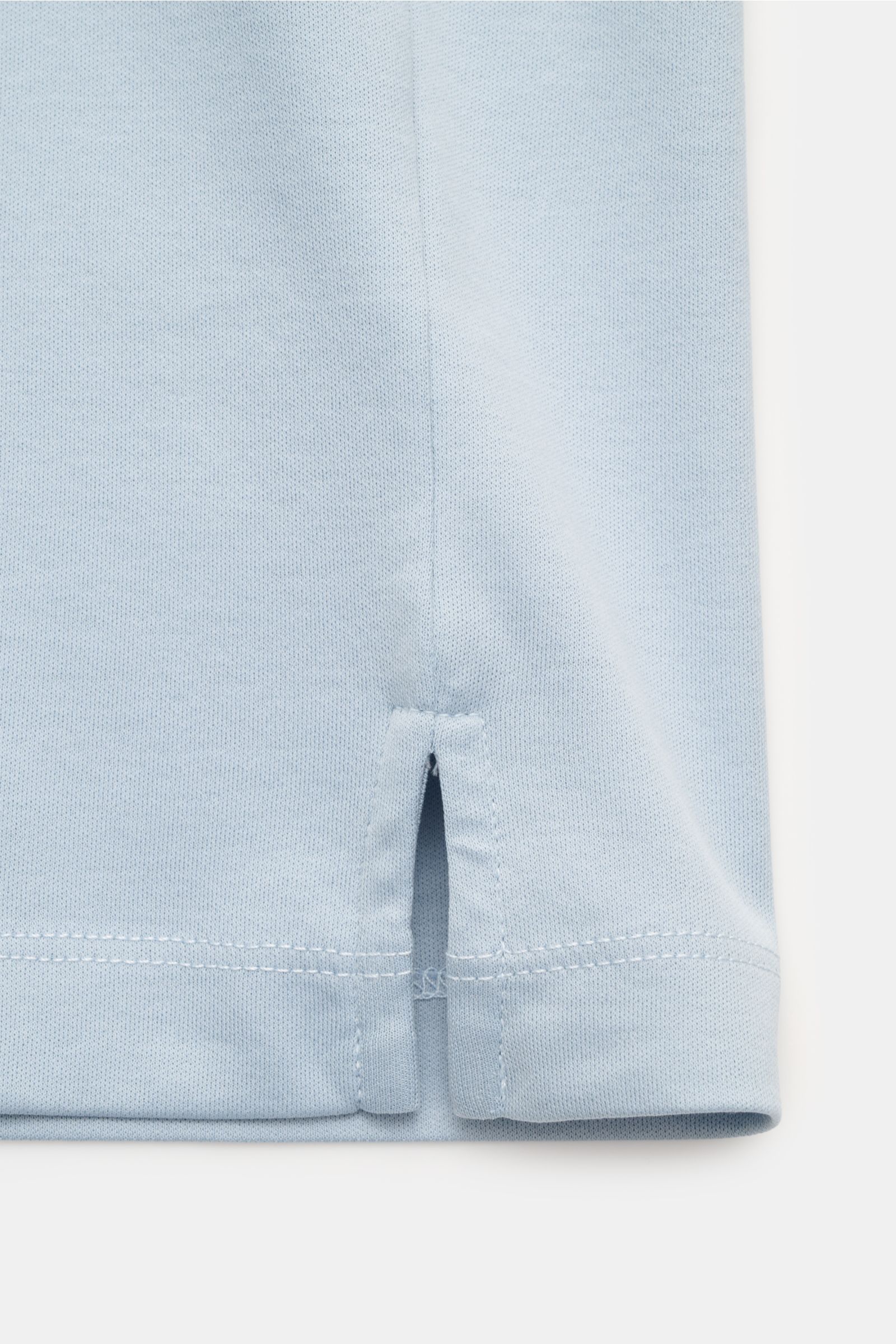 Close-up side hem view of the Aurélien Jersey-Poloshirt hellblau showing short side slits and smooth light blue cotton fabric. Vielseitiges Basic für den Frühling und Sommer: Das Jersey-Poloshirt von AURÉLIEN verbindet langstaplige, ägyptische Baumwolle m