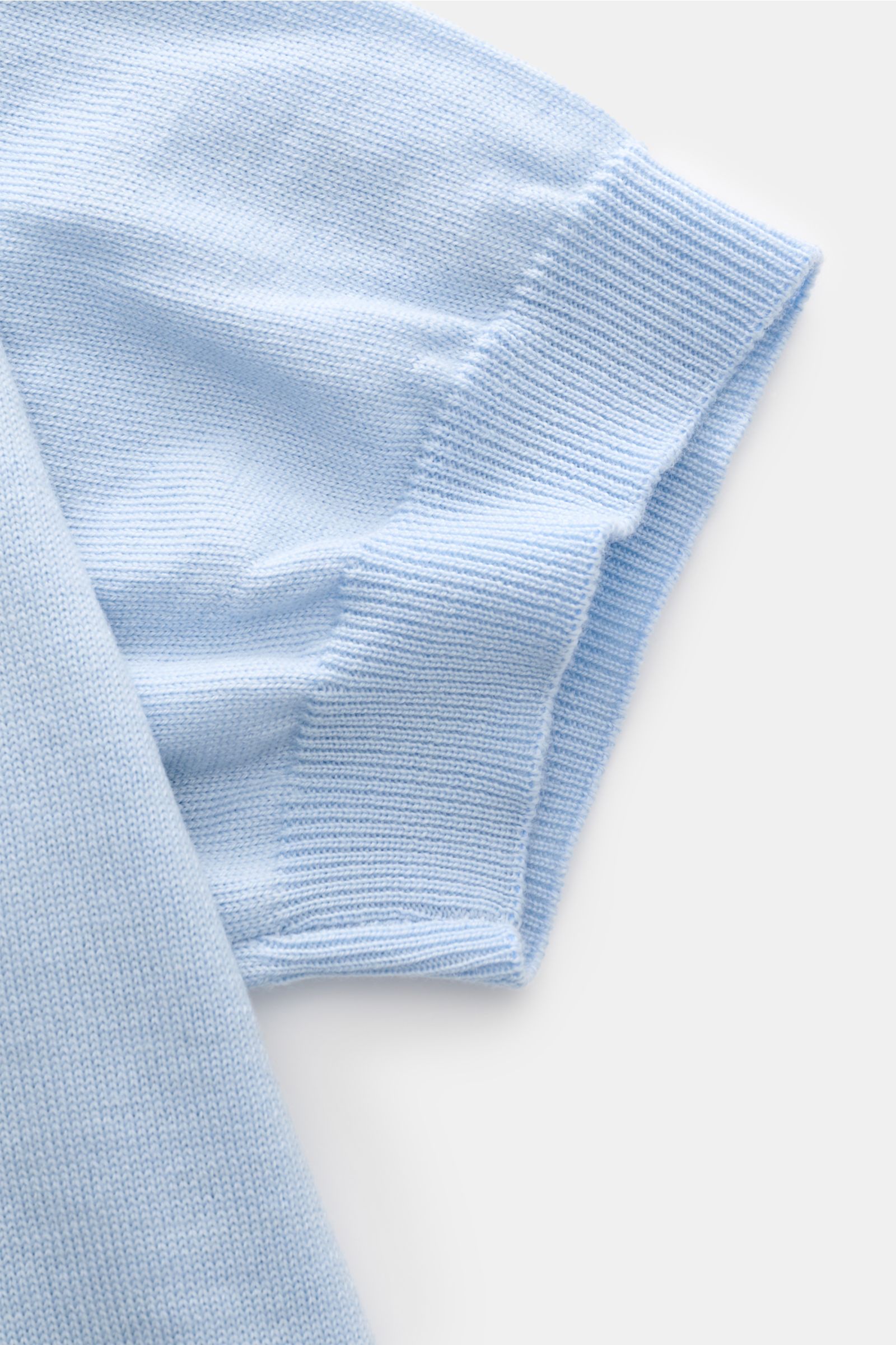 Close-up side view of Aurélien Kurzarm-Strickpolo 'Cashwool' hellblau sleeve showing fine knit, soft merino wool, slim fit ribbed cuff, classic polo collar, and open placket, a spring essential with exquisite texture and timeless silhouette.